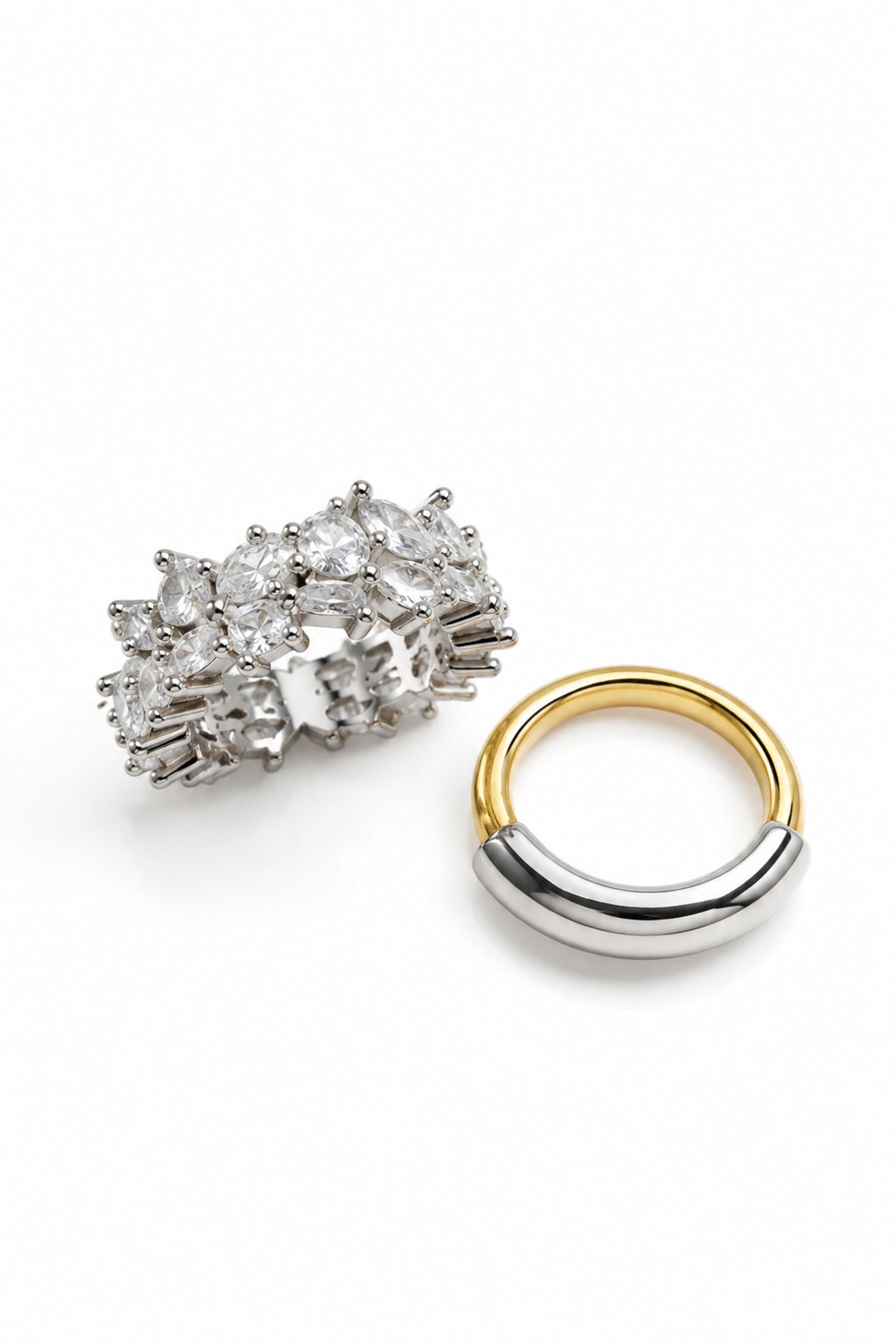 Crystal-set cluster ring beside a gold and silver two-tone band on white