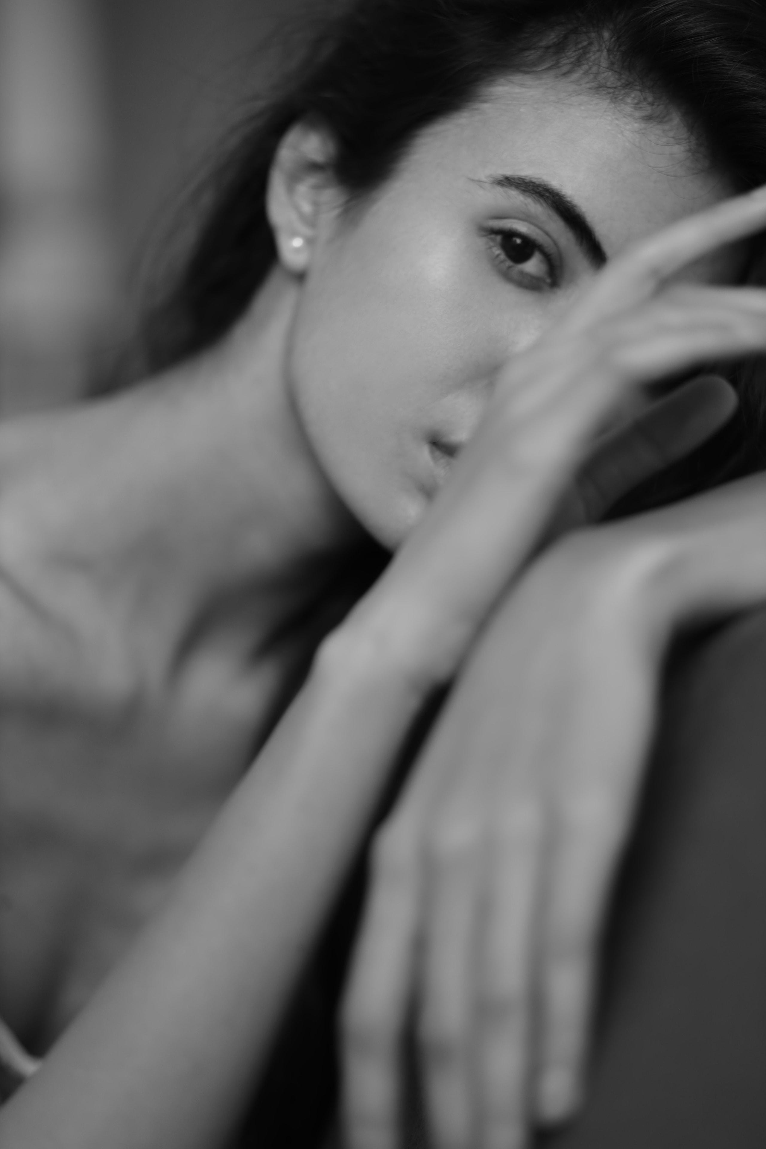 Black-and-white close-up of woman's face resting on arm, one eye visible, shallow focus