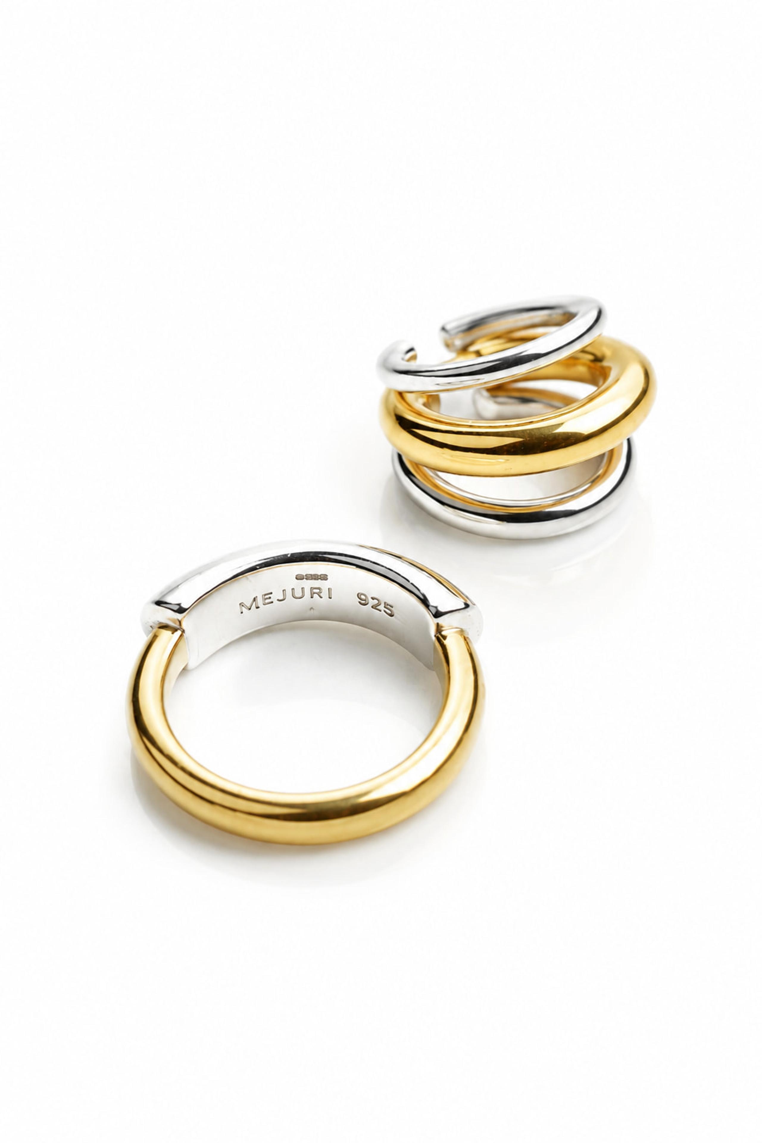 Set of glossy gold and silver Mejuri stacking rings on bright white surface