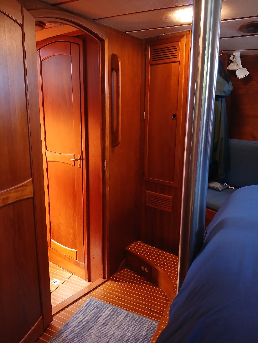 Comfortable master stateroom with burgundy bedding and wood paneling