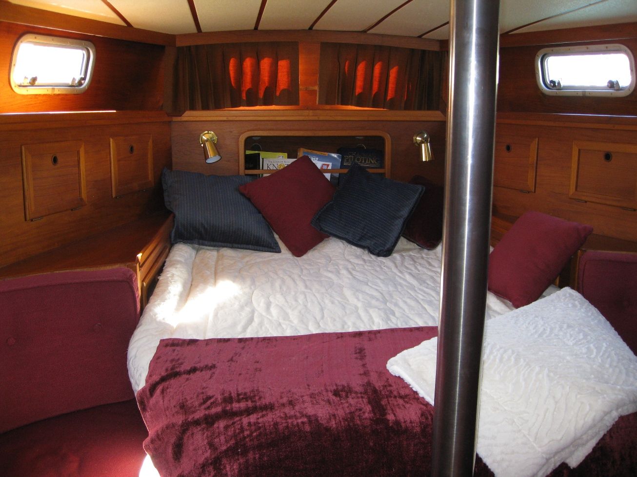 Comfortable master stateroom with burgundy bedding and wood paneling