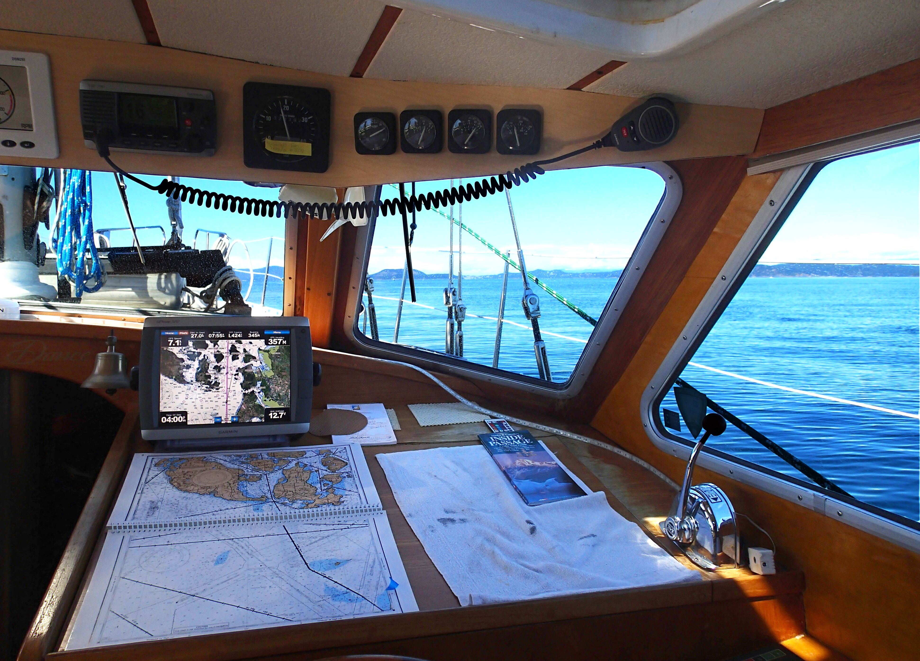 Navigation station with charts, instruments, and view of Alaska waters
