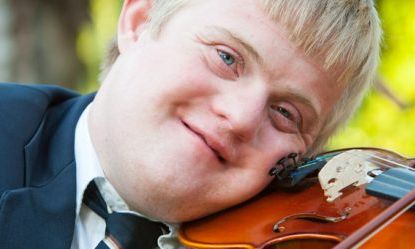 A headshot of a person with Down Syndrome playing the violin
