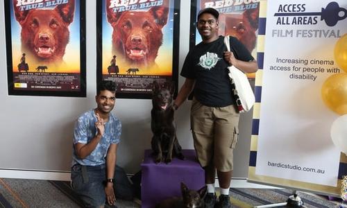 Two people standing and kneeling next to a dog at a film premier