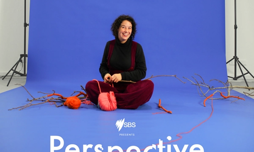 A woman sitting on a film set and knitting, the words 'Perspective Shift exploring new dimensions' appear