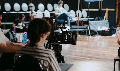A woman with long dar hair being interviewed on a film set