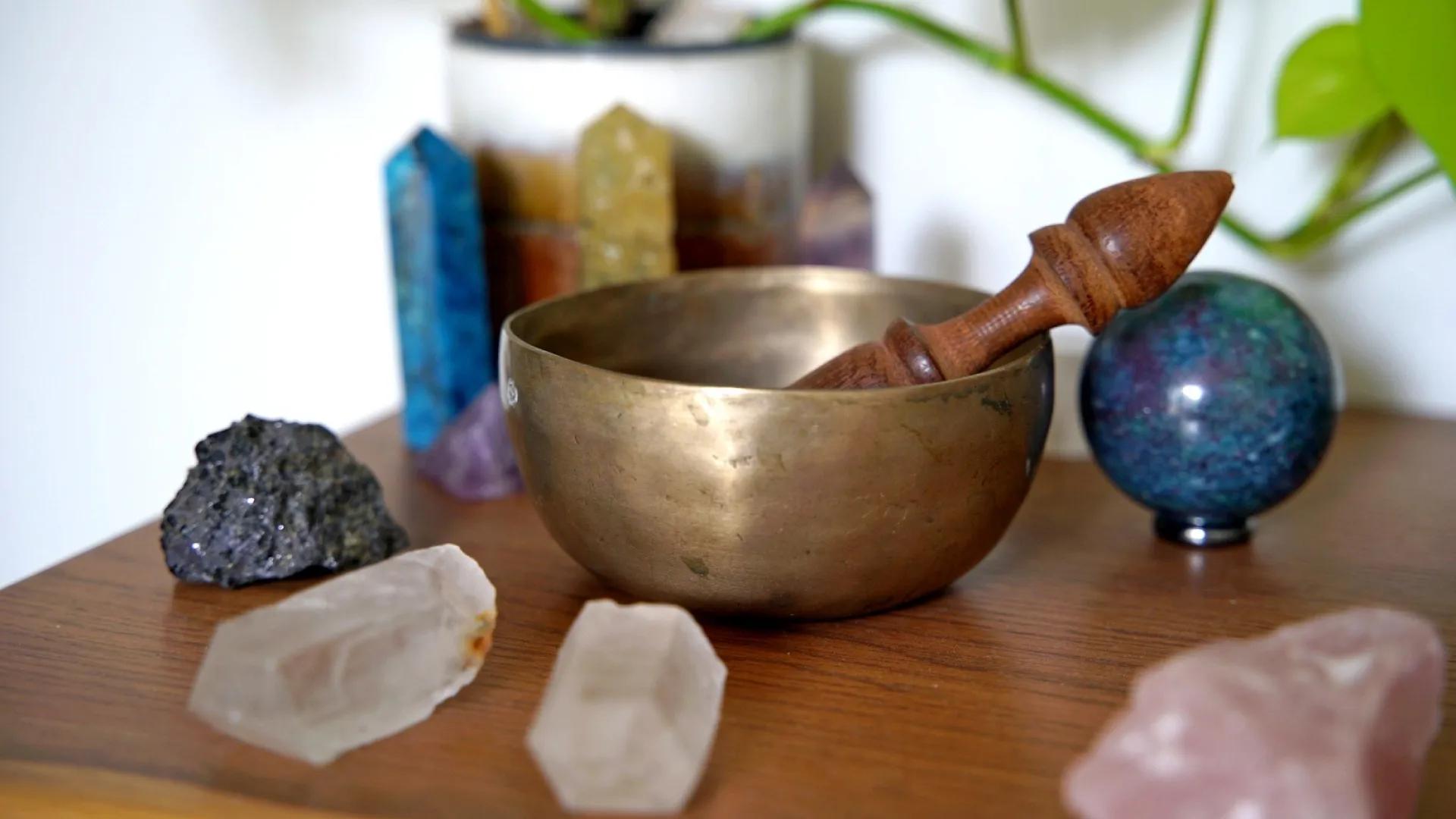 A photo of a brass bowl with some gemstones sitting around it.