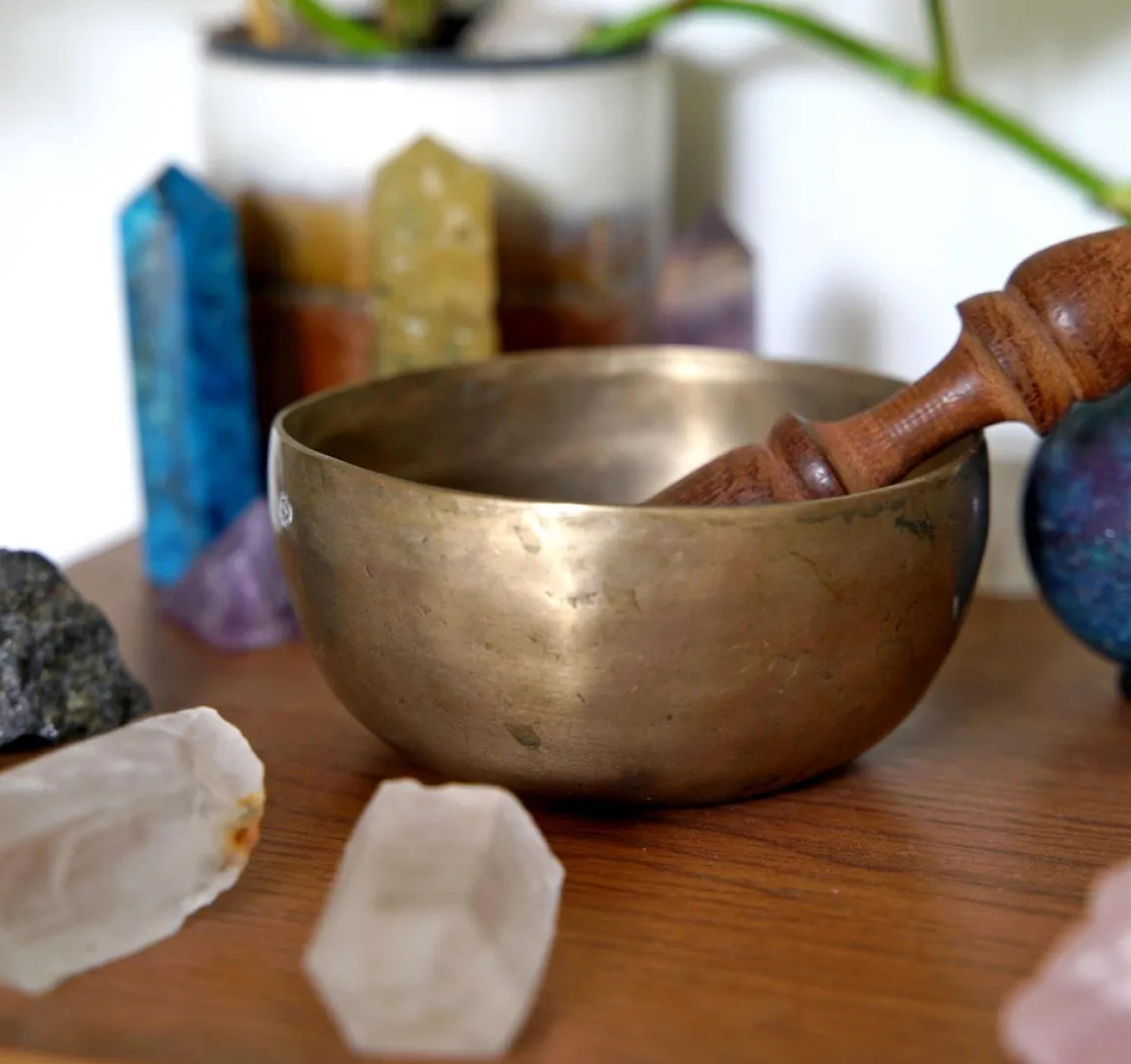 A photo of a brass bowl with some gemstones sitting around it.
