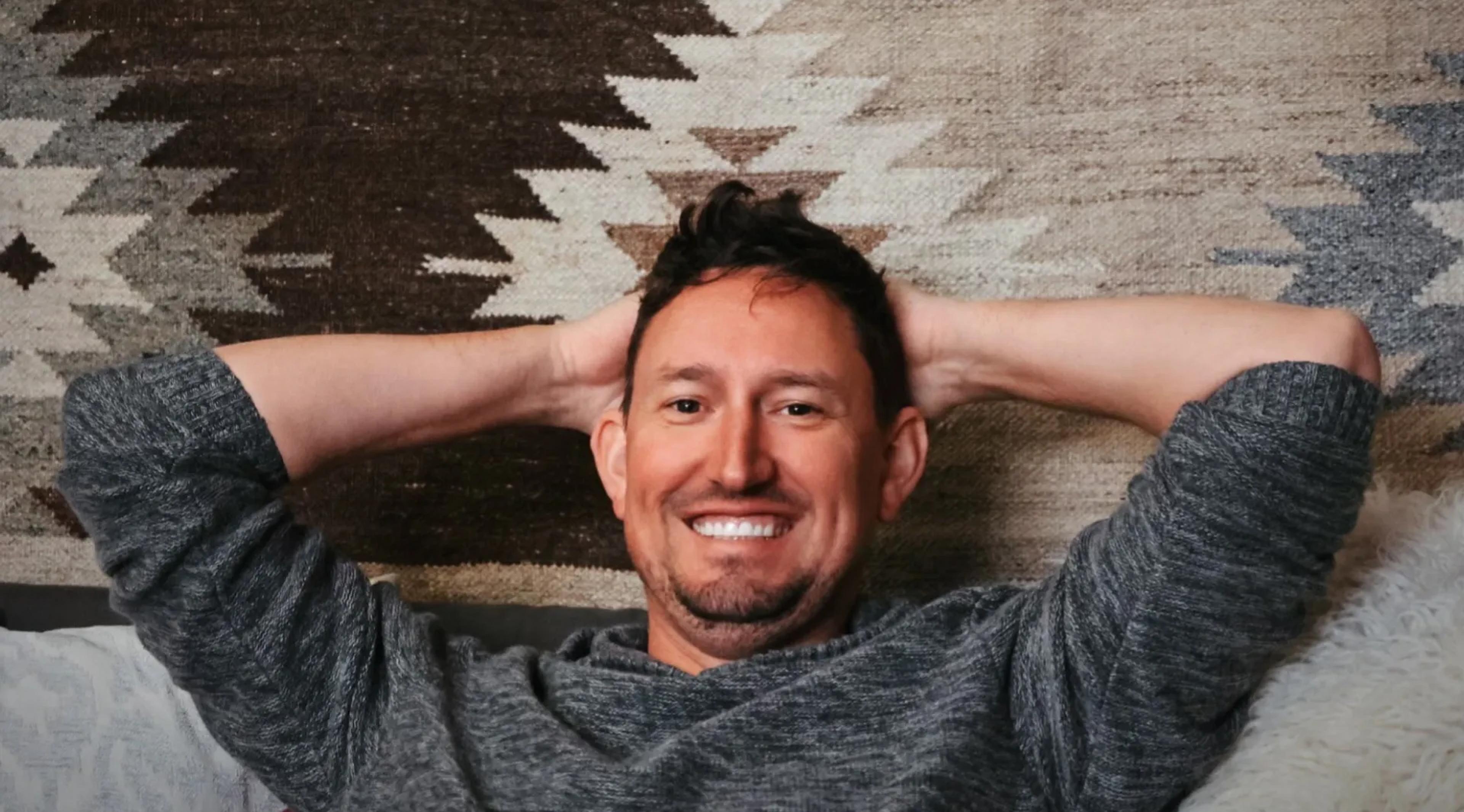 A photo of David lying back with his hands behind his head.