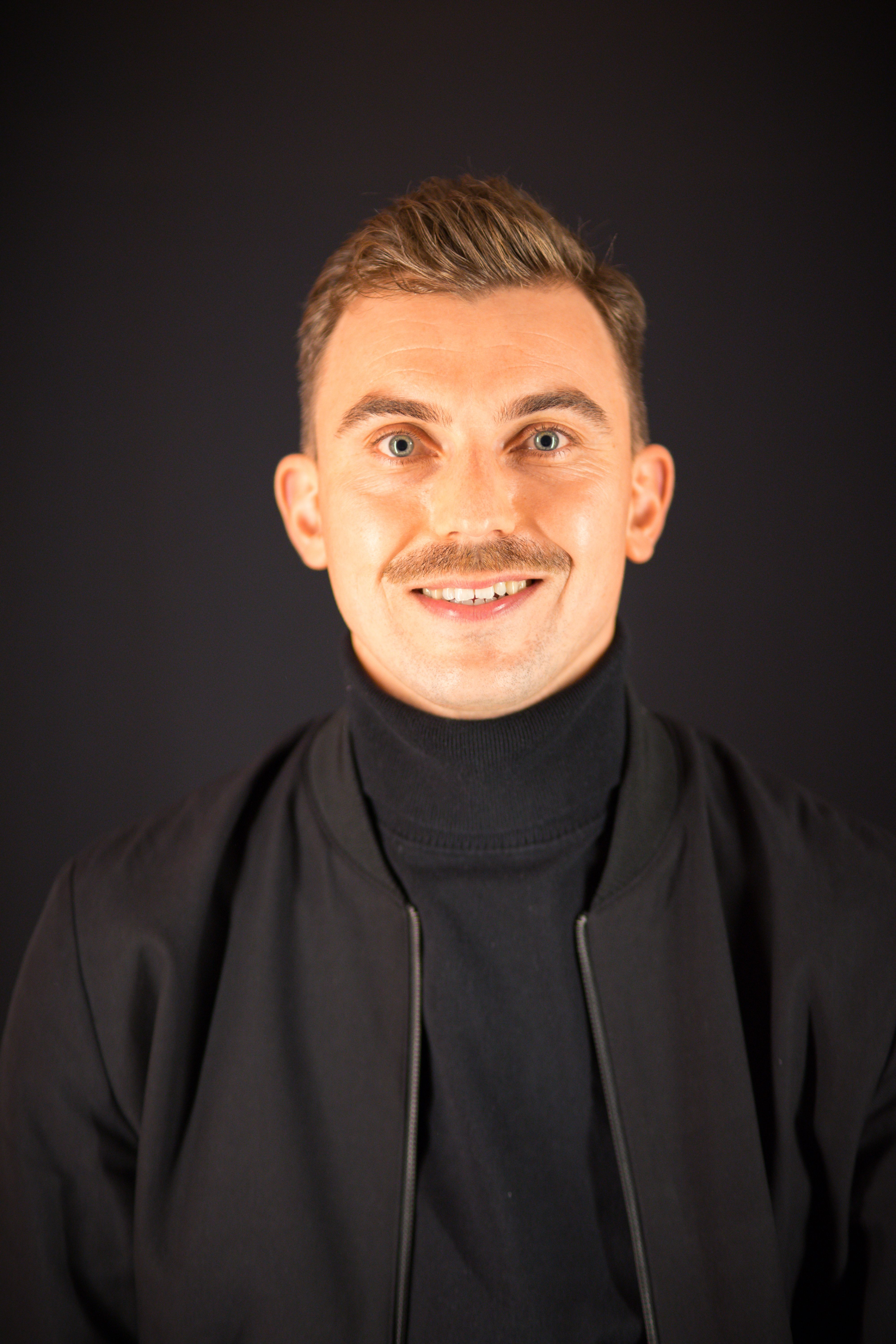 Man with a mustache wearing a black jacket.