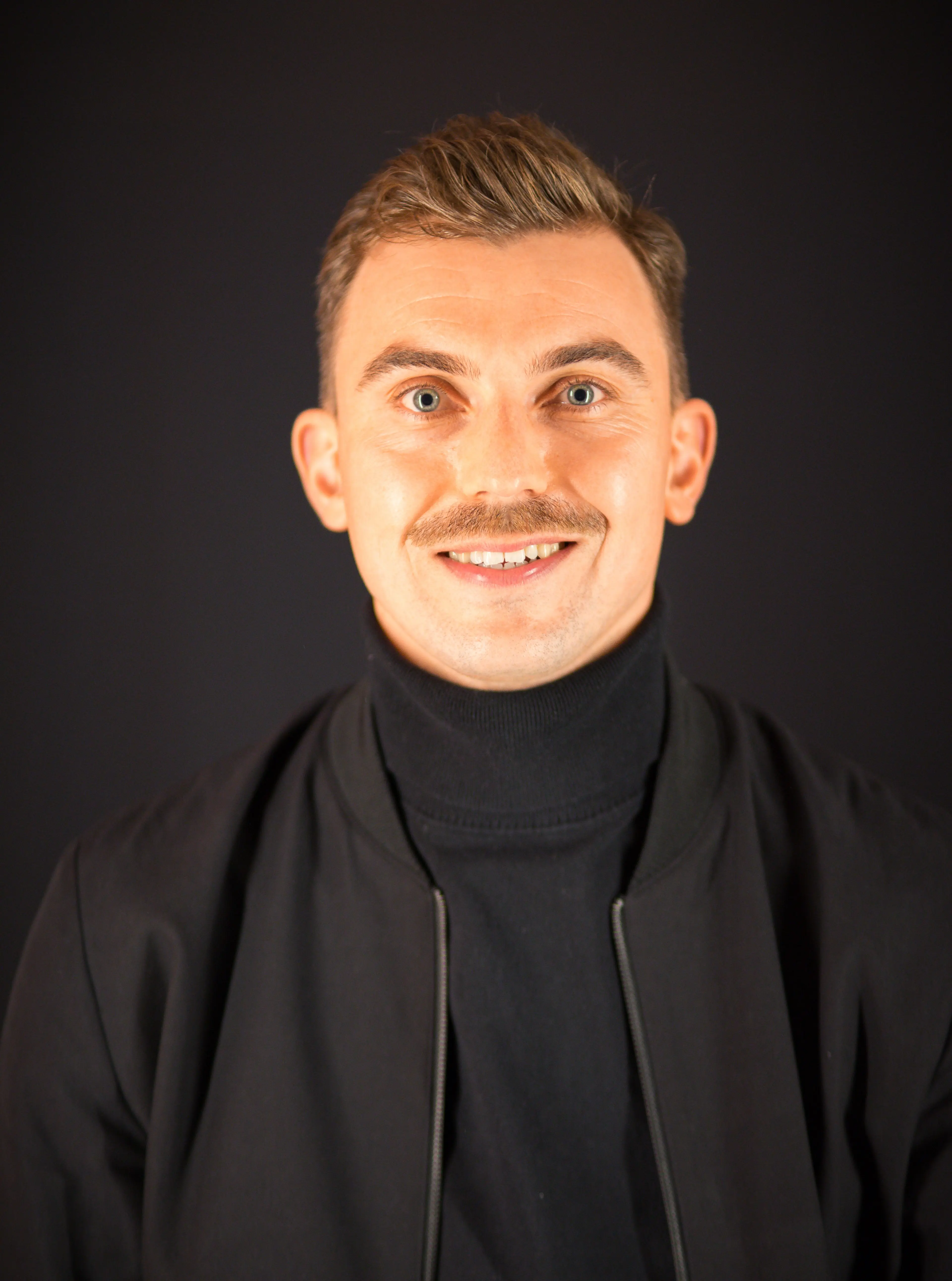 Man with a mustache wearing a black jacket.