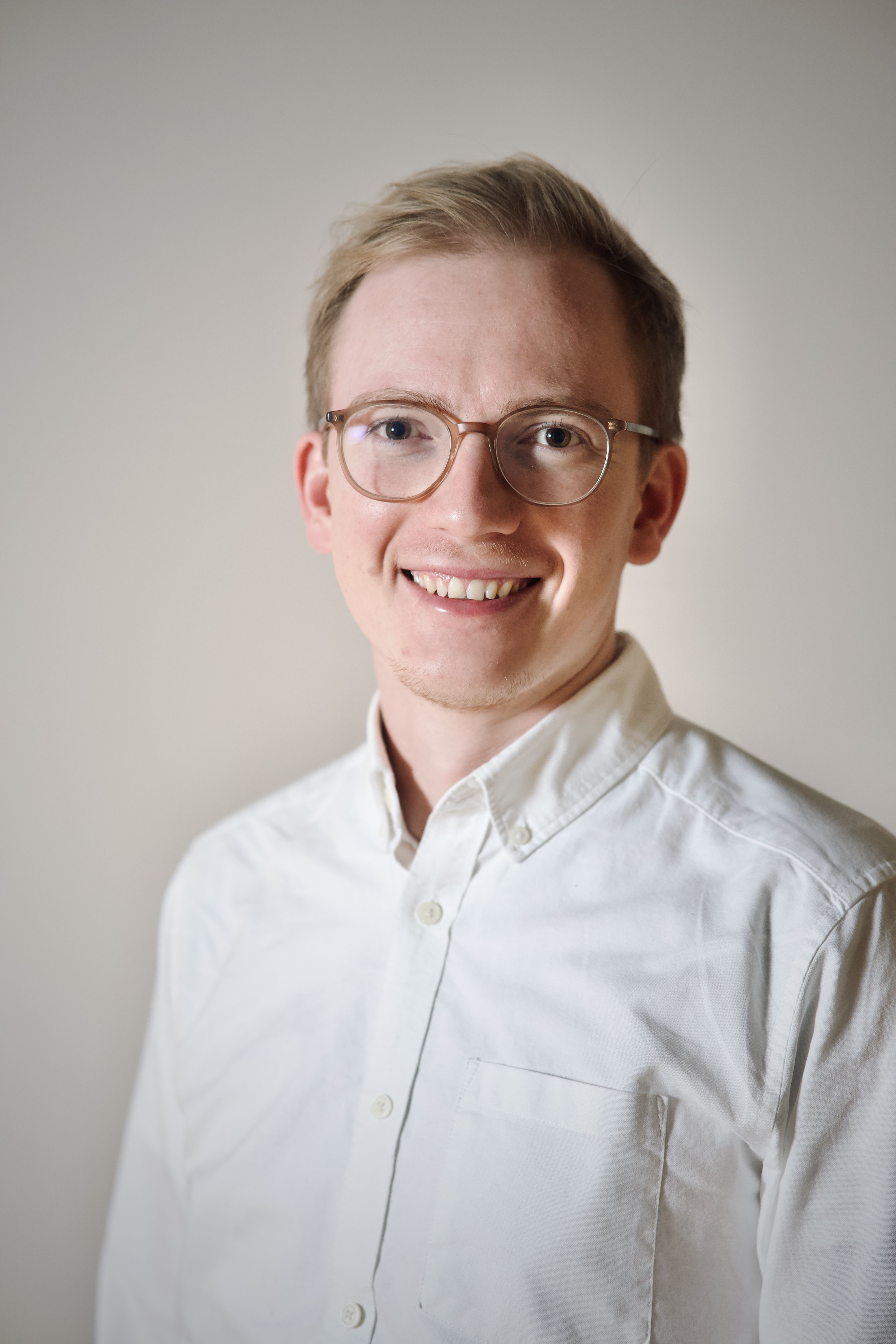 Blonde man with glasses and a white shirt.