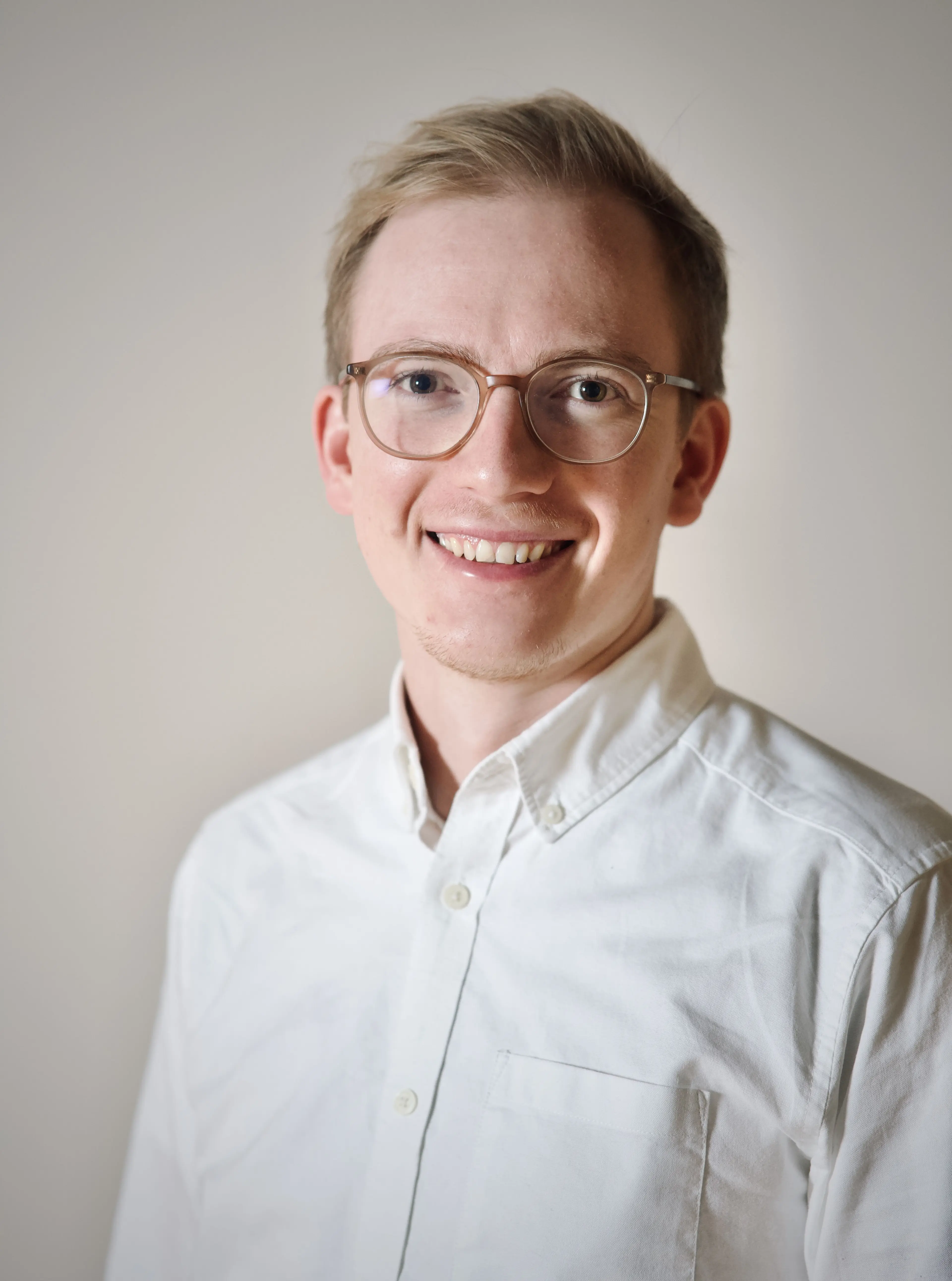 Blonde man with glasses and a white shirt.