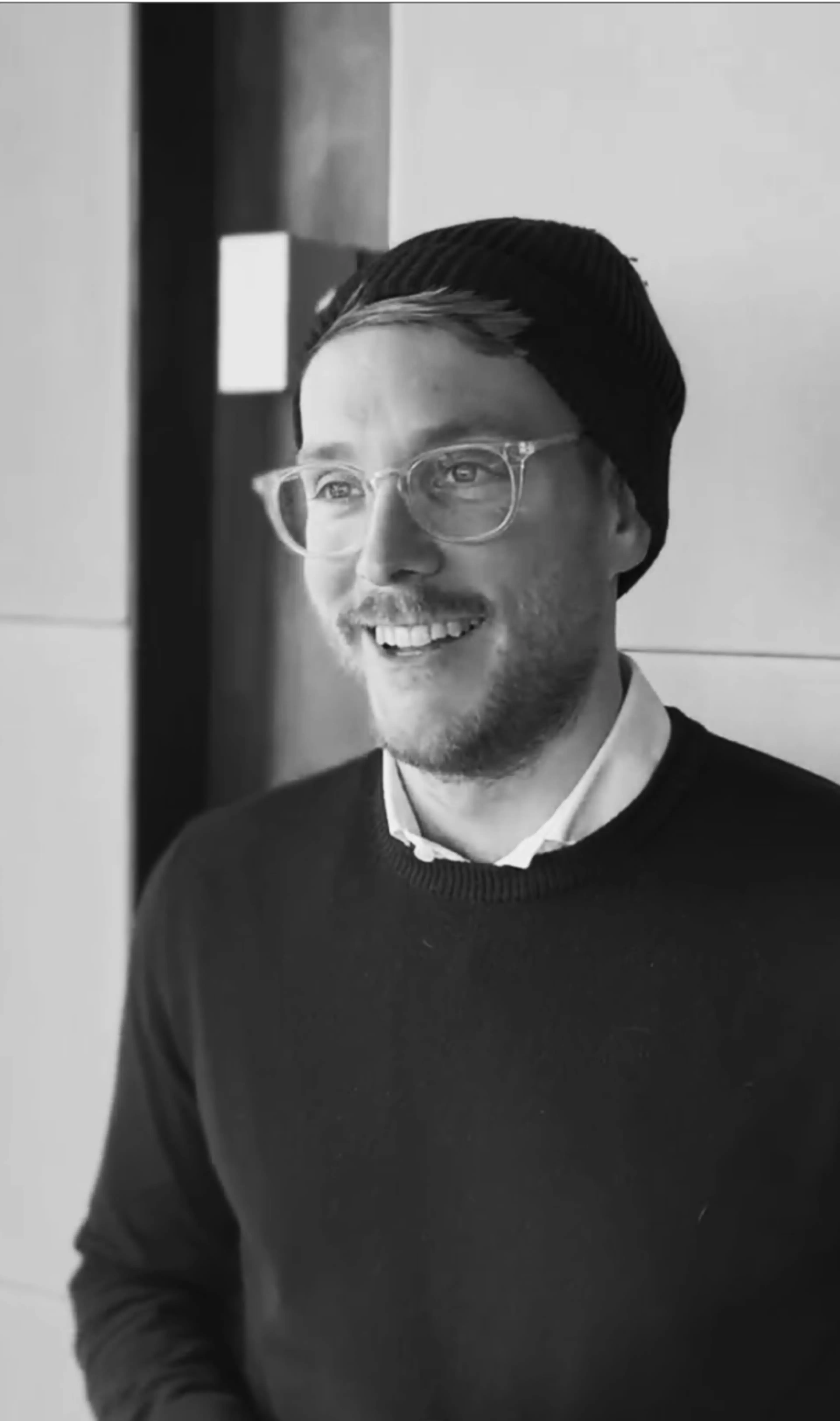 Man with glasses and beanie in black and white
