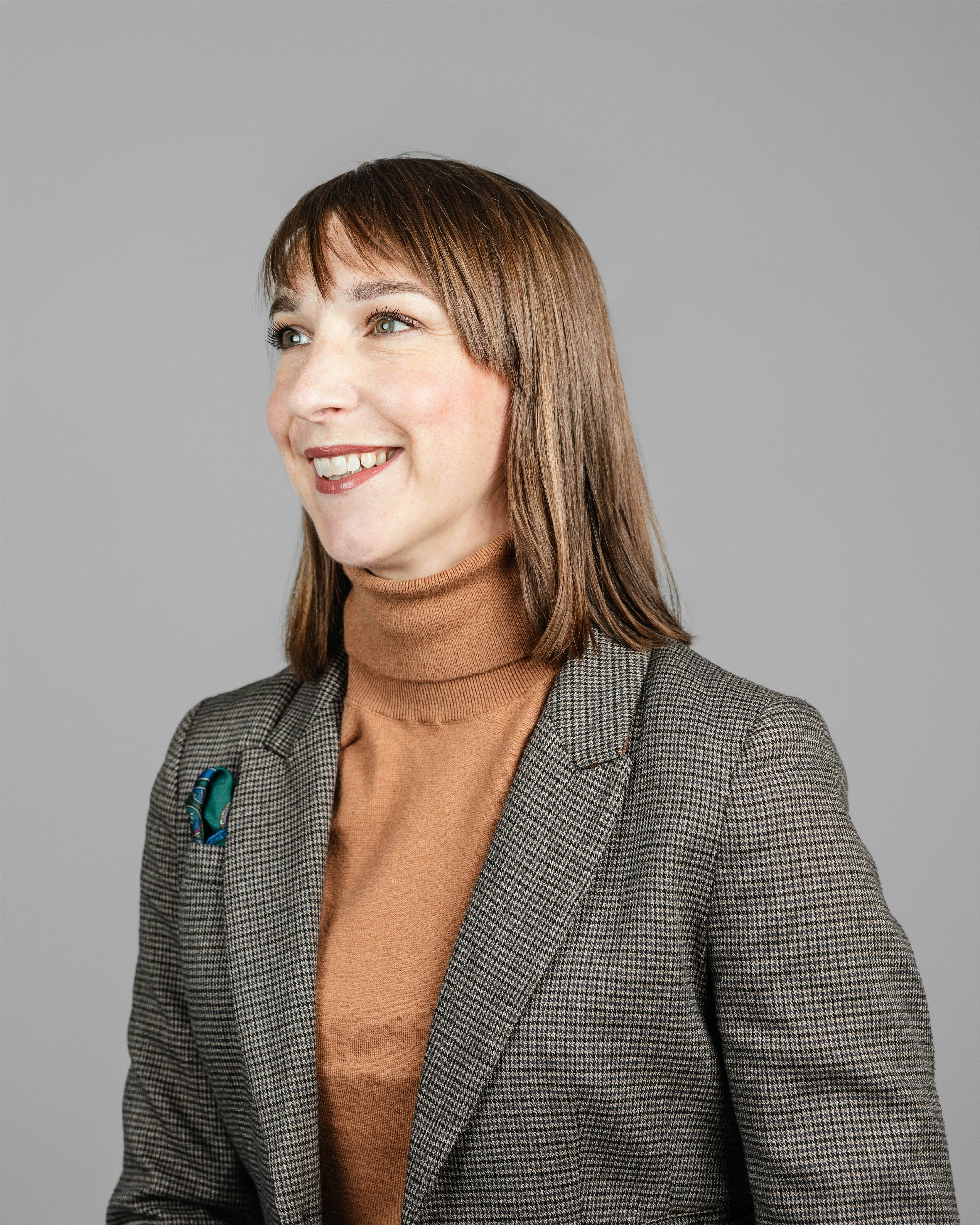 Woman with brown hair, smiling and looking to the left