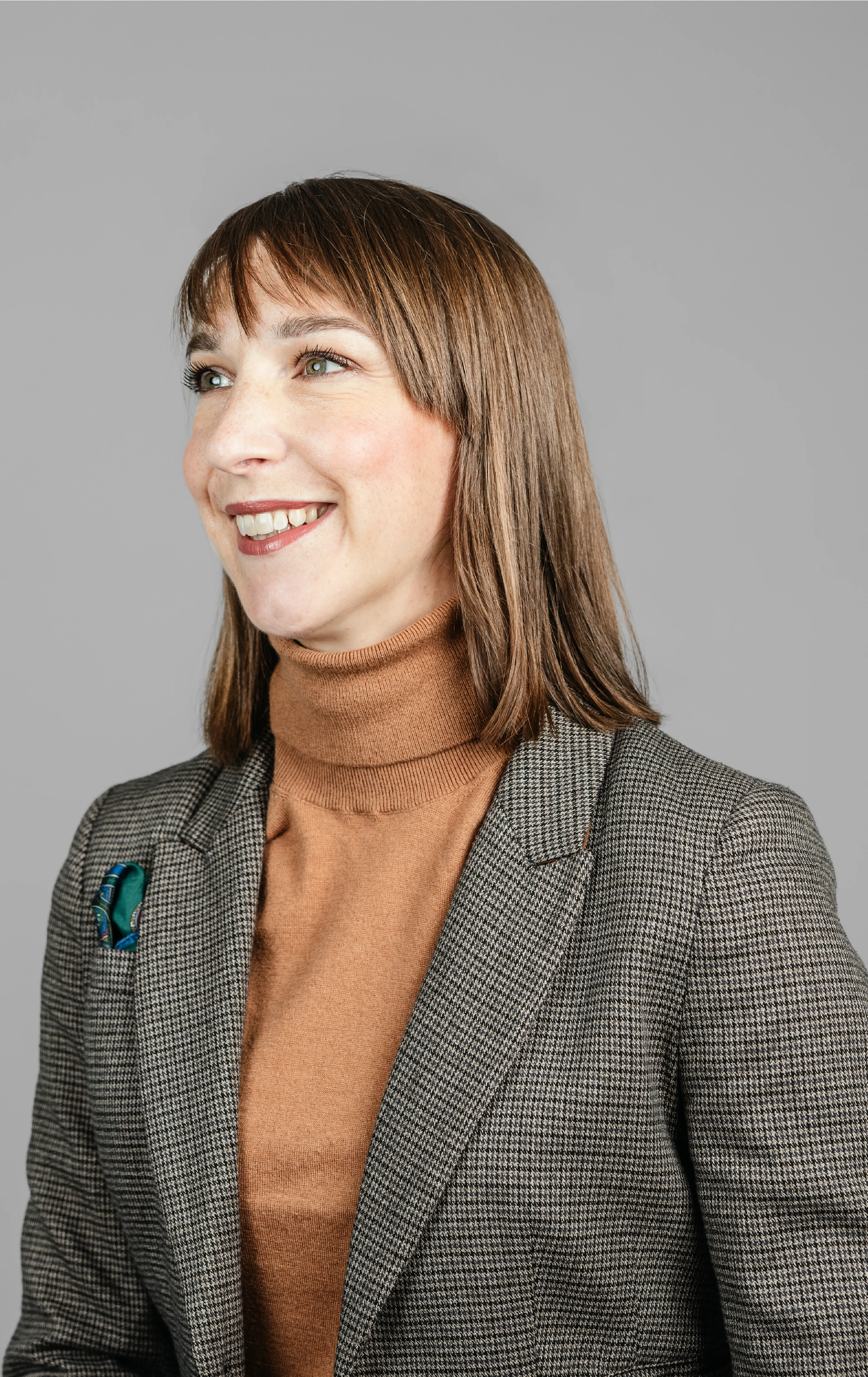 Woman with brown hair, smiling and looking to the left