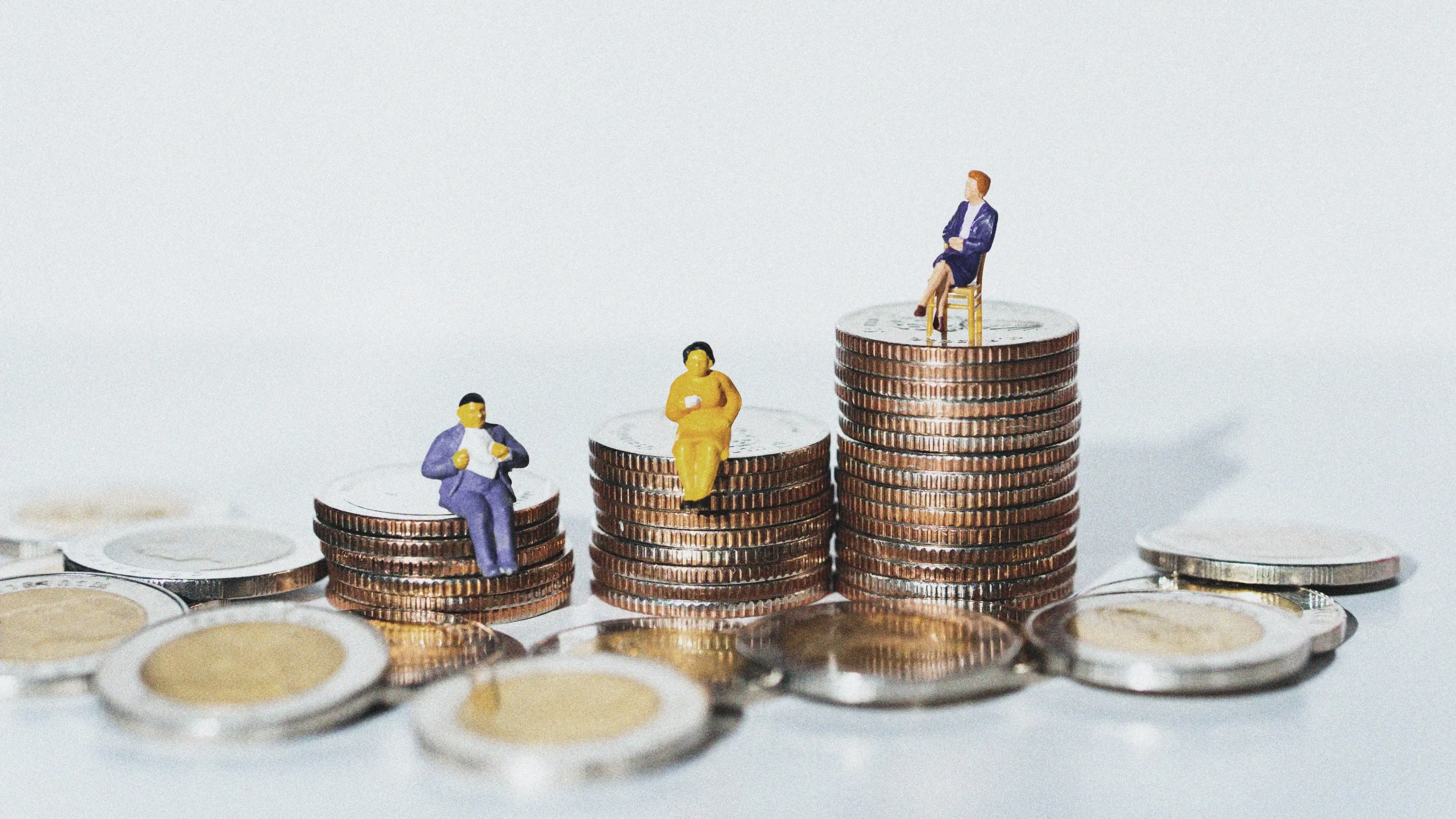 Small human figures on pile of coins