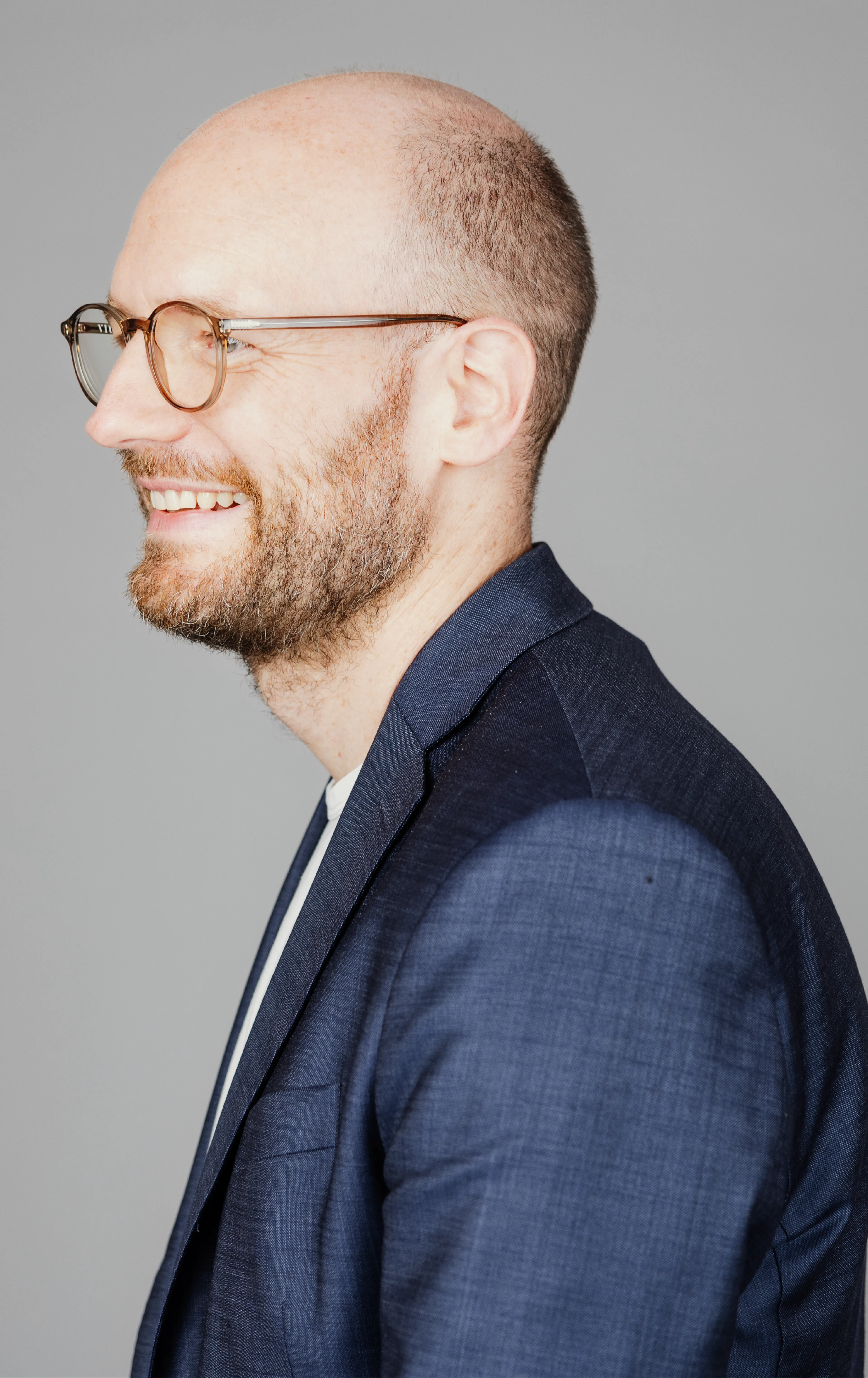 A man with glasses smiling and facing the left