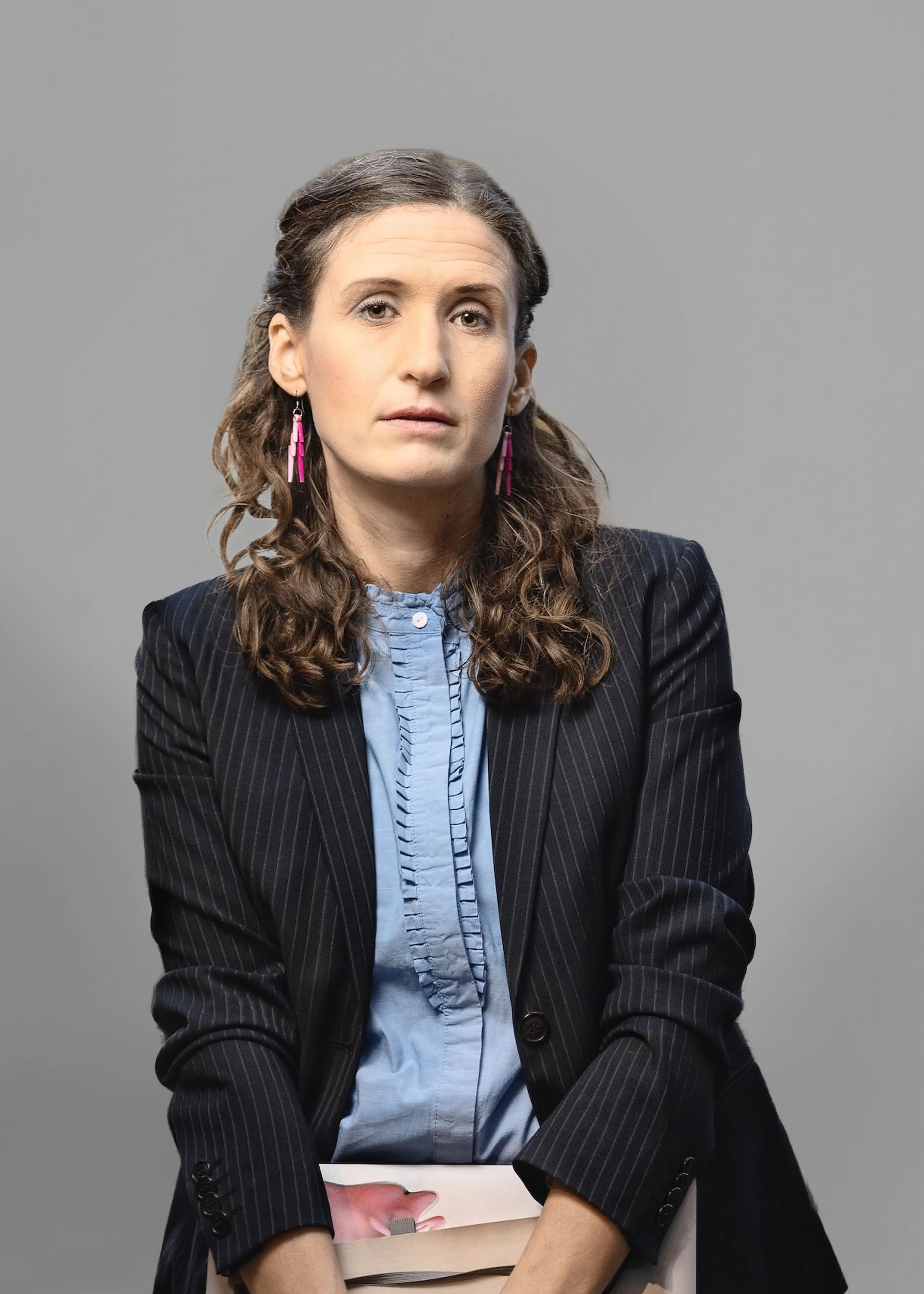 Woman wearing a blazer and a light blue shirt.