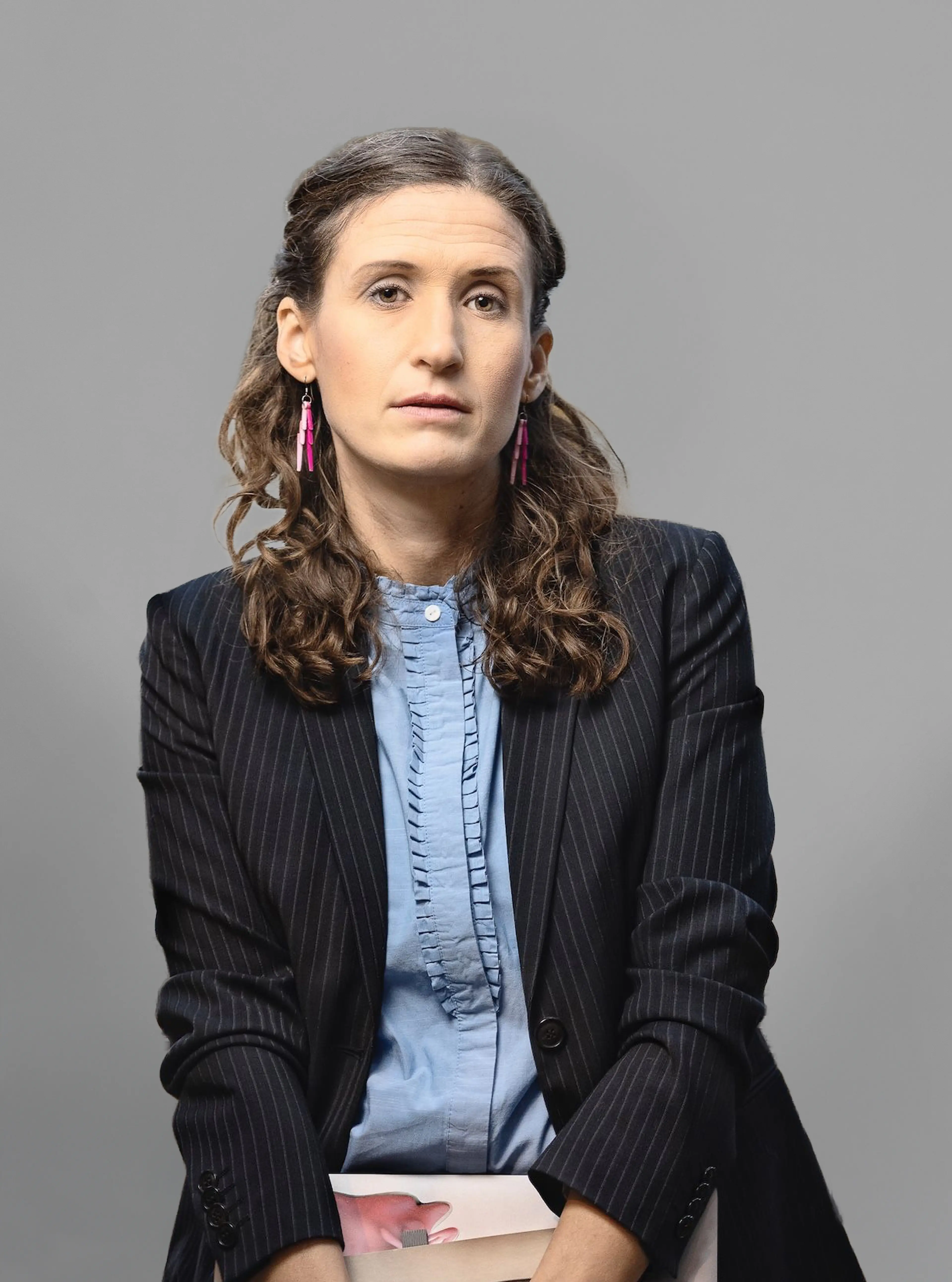 Woman wearing a blazer and a light blue shirt.