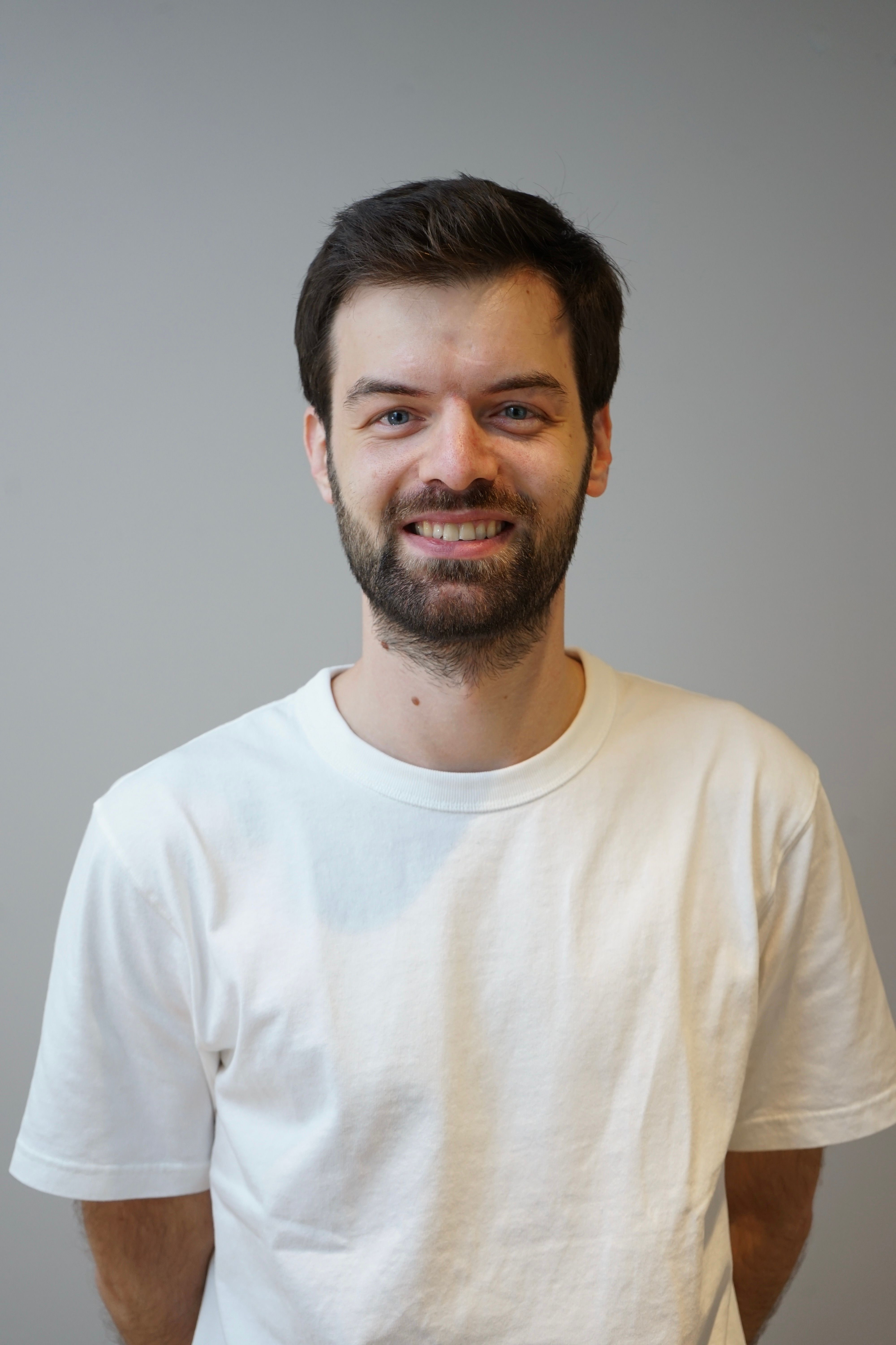 Smiling man wearing a white t-shirt.