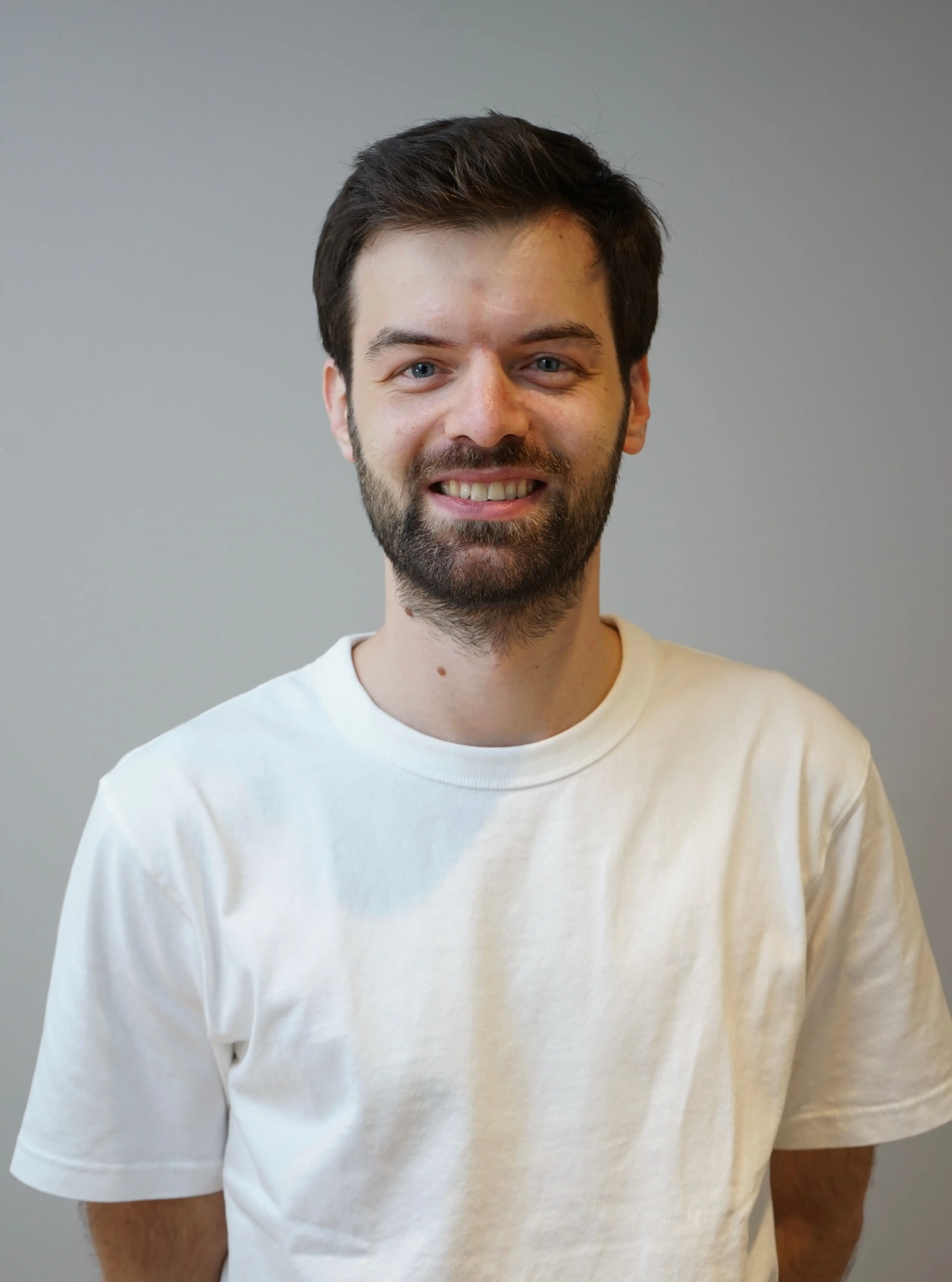 Smiling man wearing a white t-shirt.