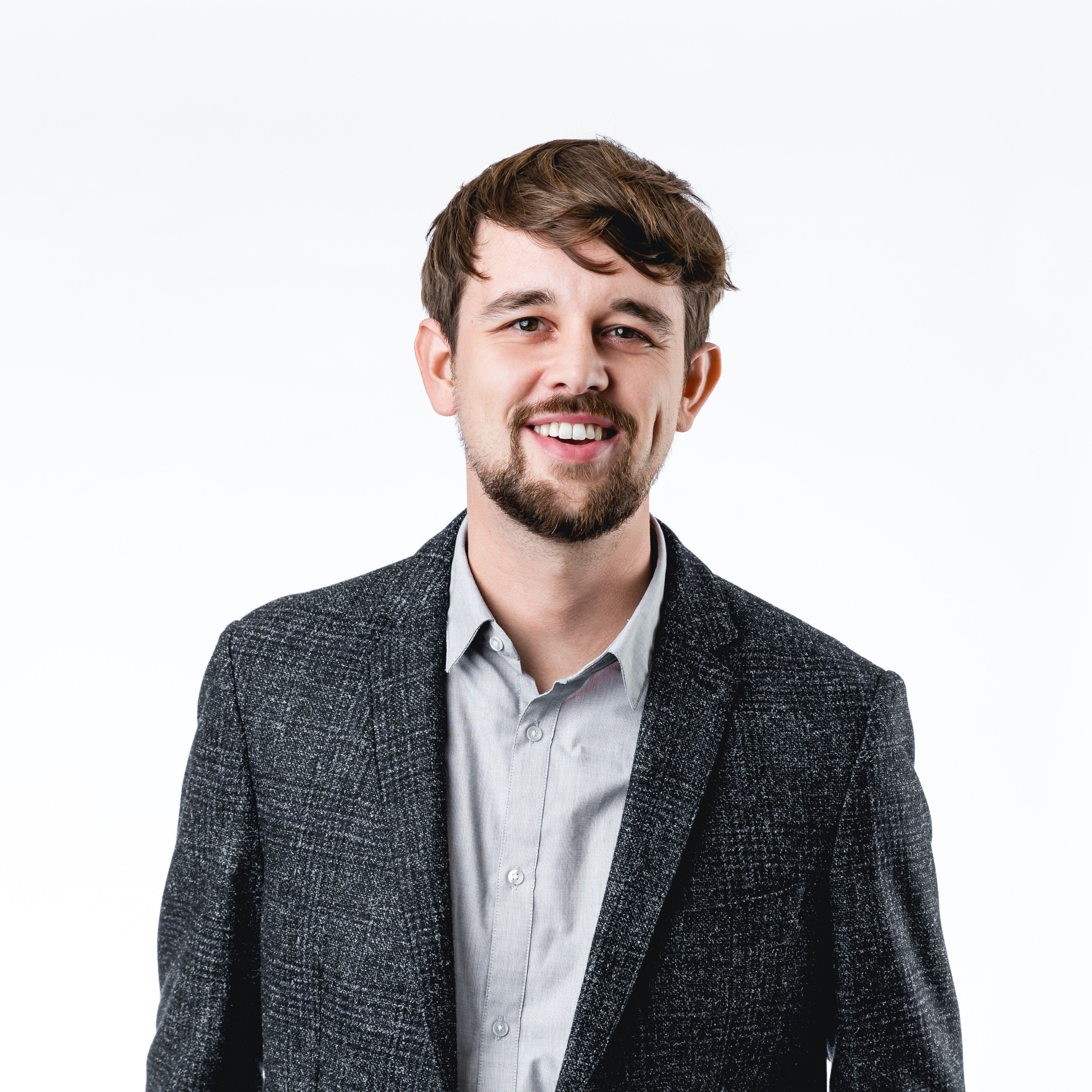 man with beard wearing a grey jacket 