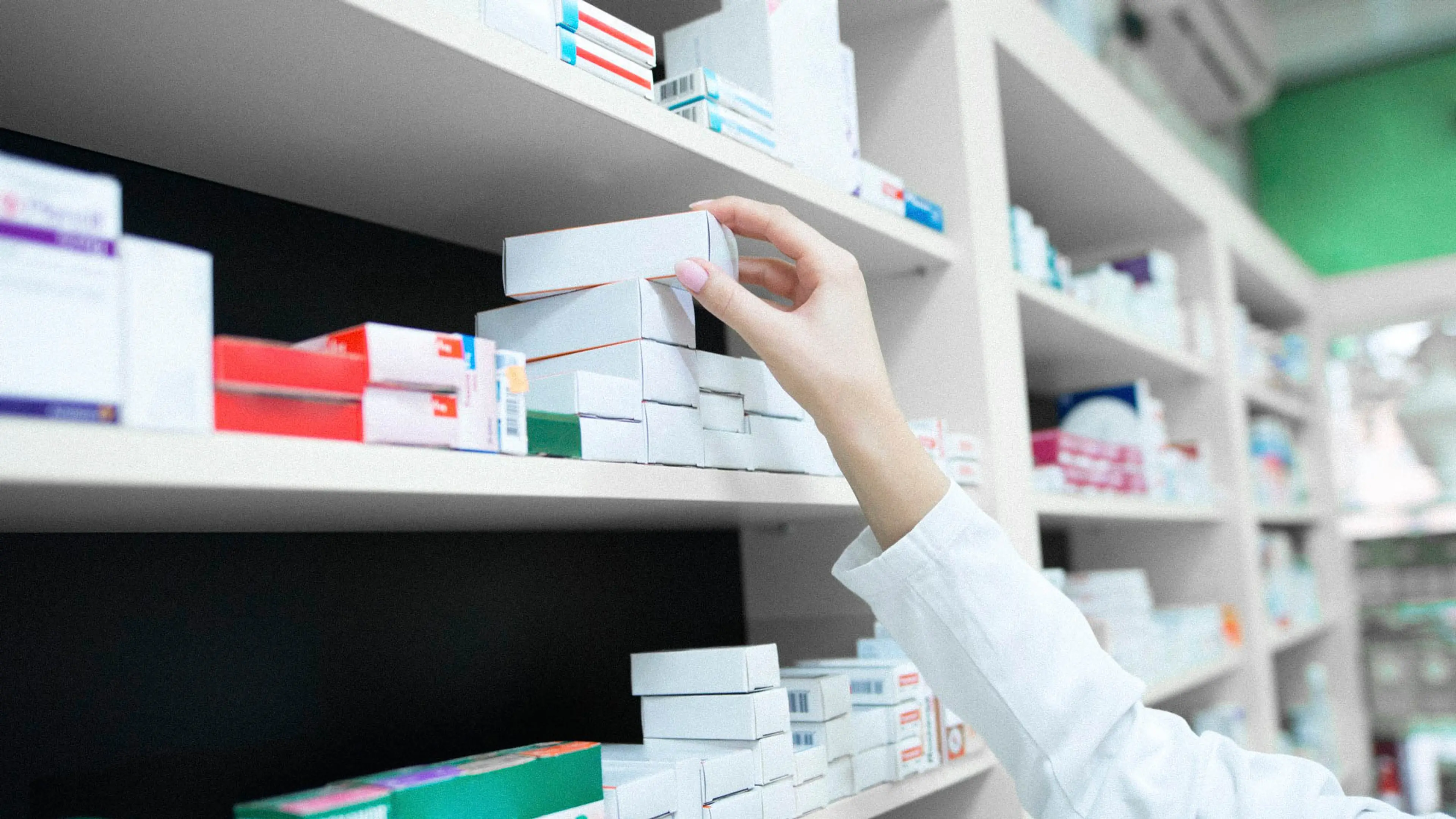Hand reaching after a package of medicine at a pharmacy