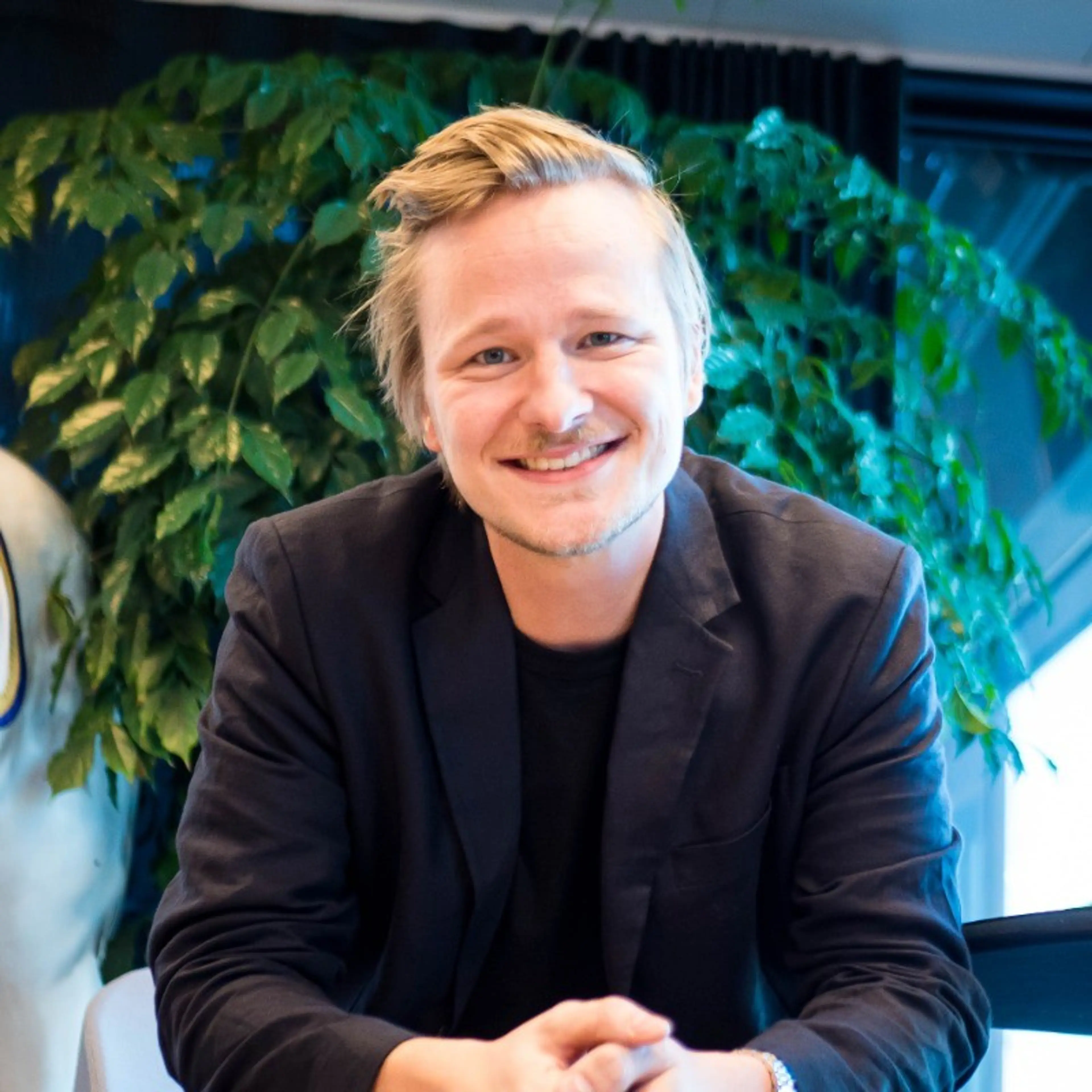 Smiling man wearing a black suit.