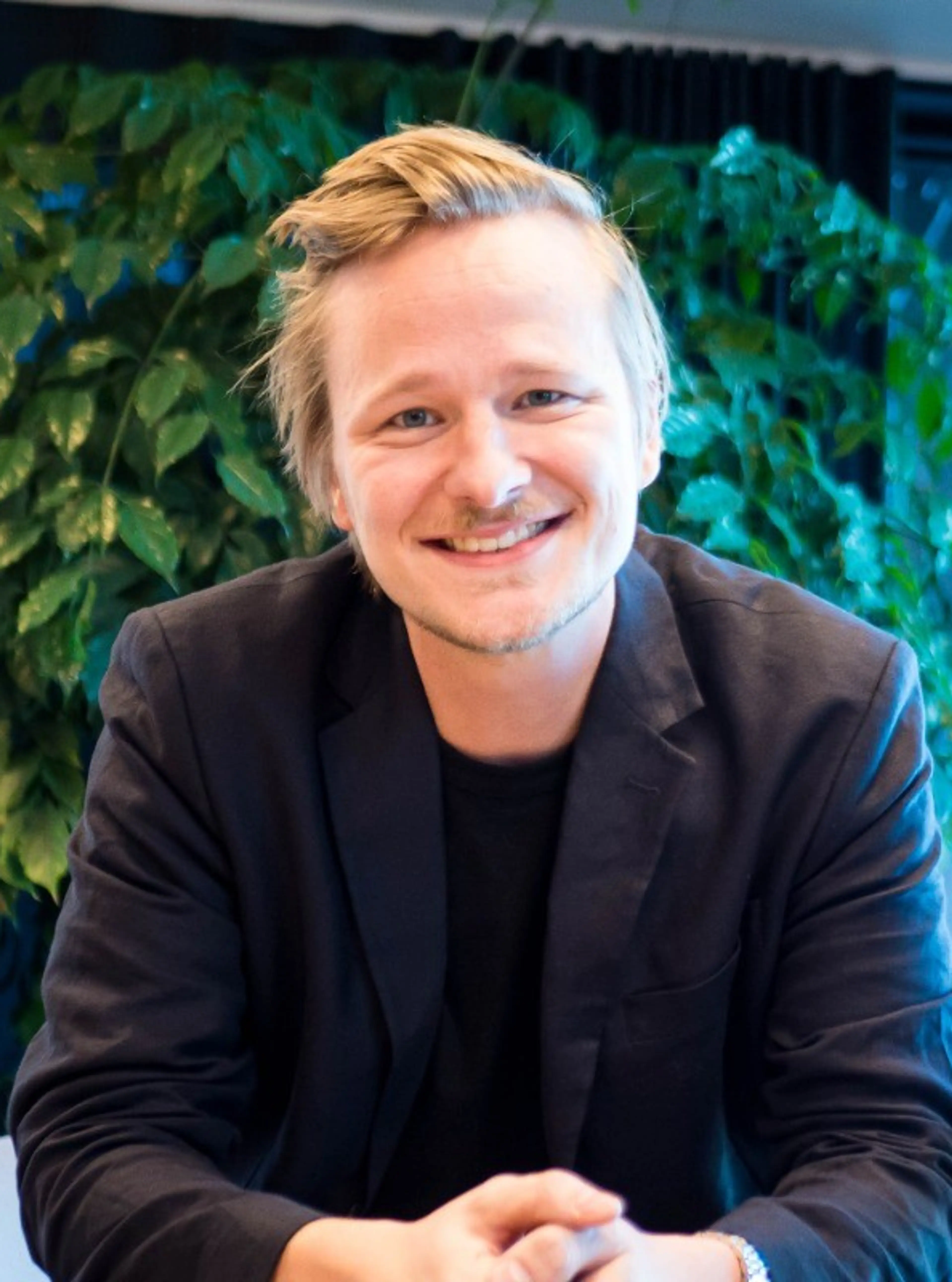 Smiling man wearing a black suit.