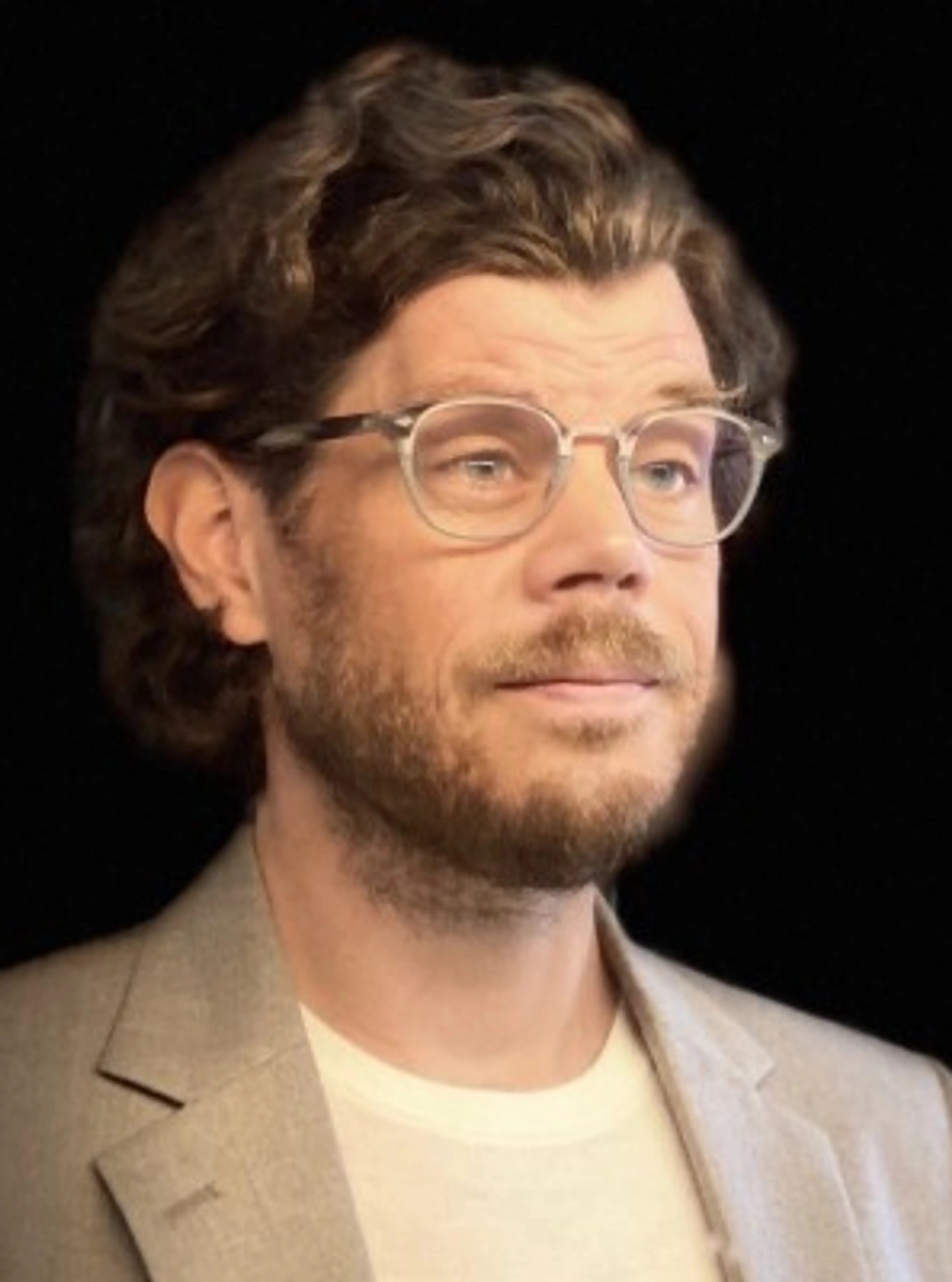 Man with glasses wearing a beige suit.
