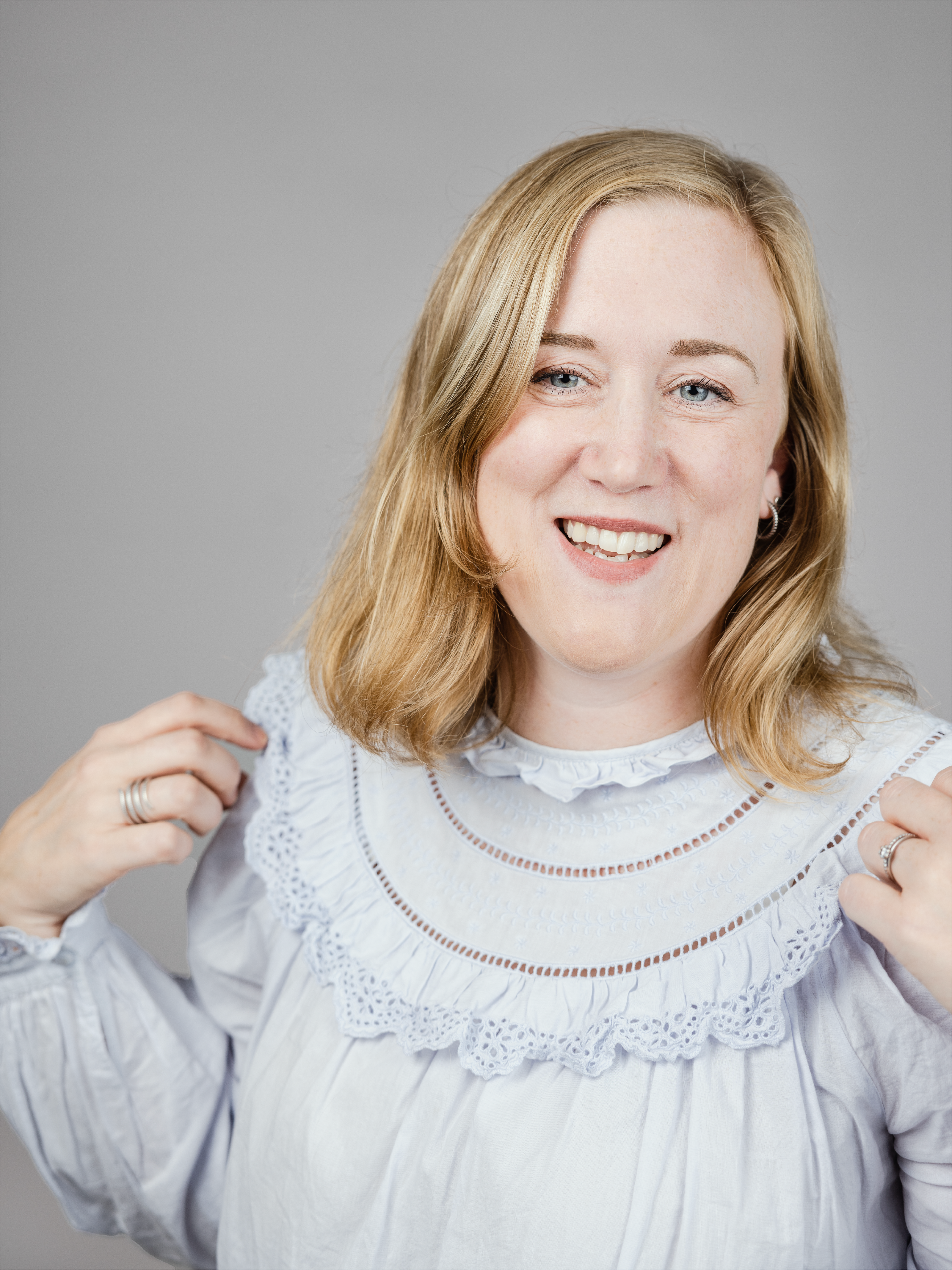 A woman with light blue blouse smiling and looking slightly to the left