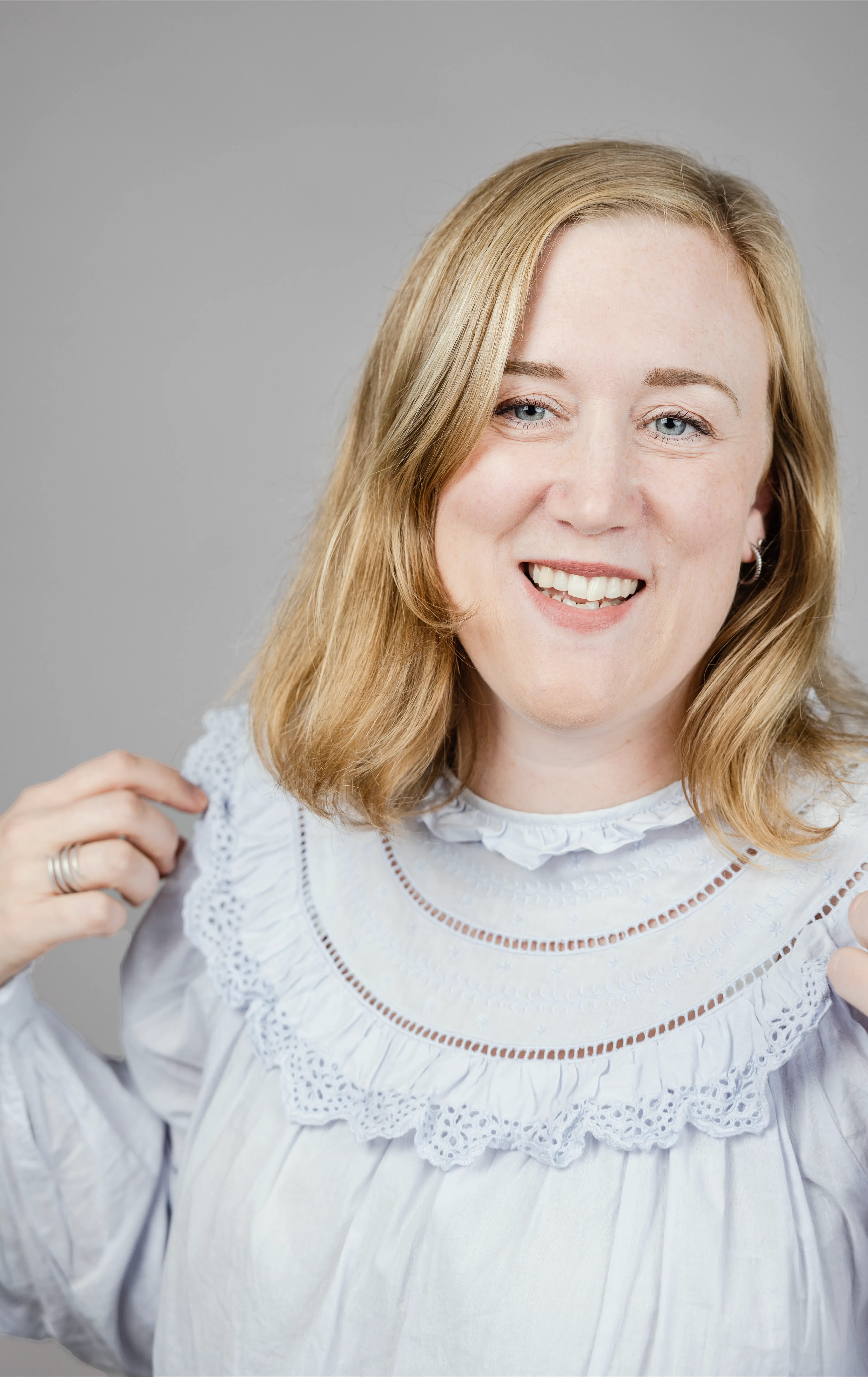A woman with light blue blouse smiling and looking slightly to the left