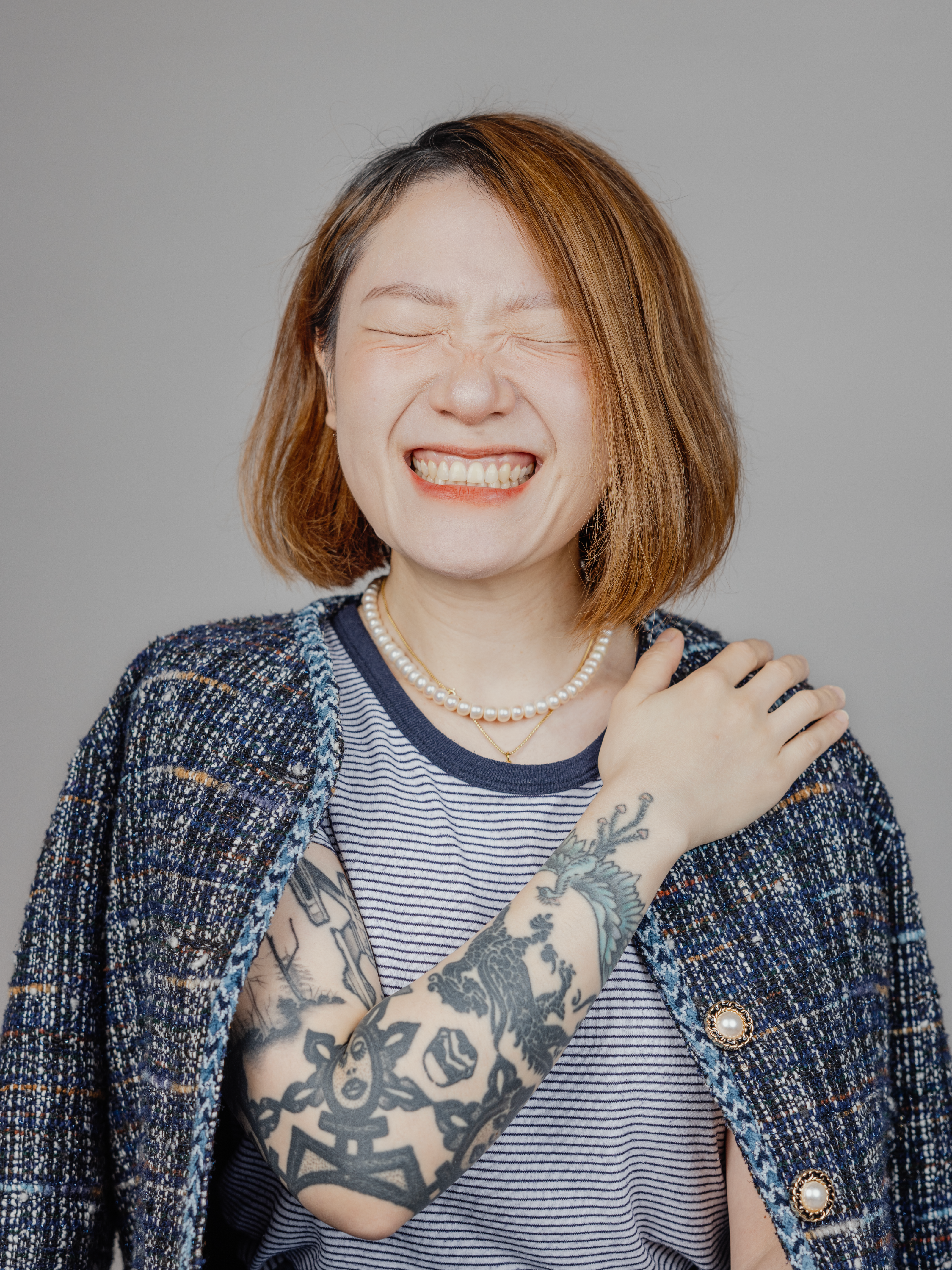 A woman with a big smile and closed eyes, and hand on her shoulder