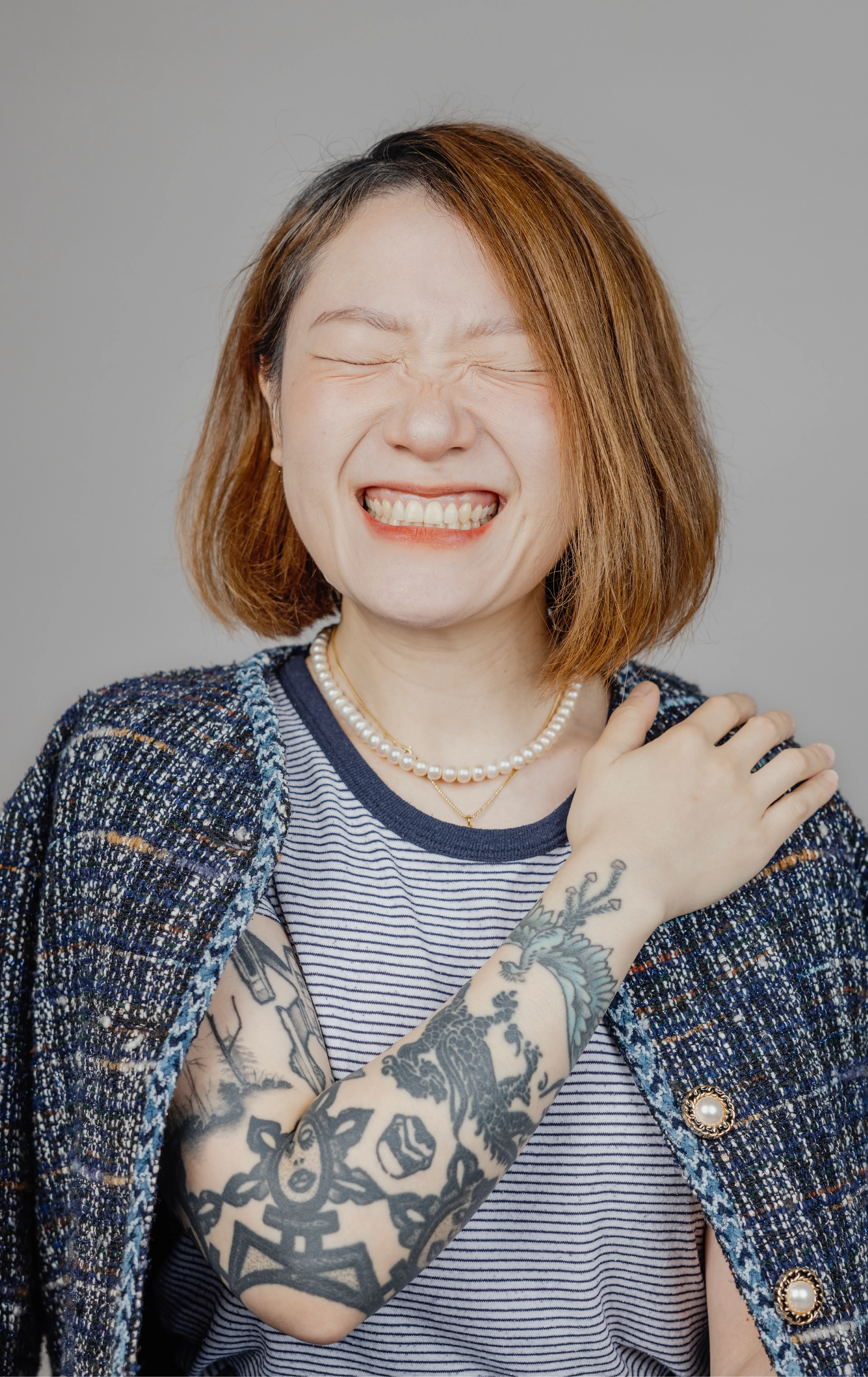 A woman with a big smile and closed eyes, and hand on her shoulder