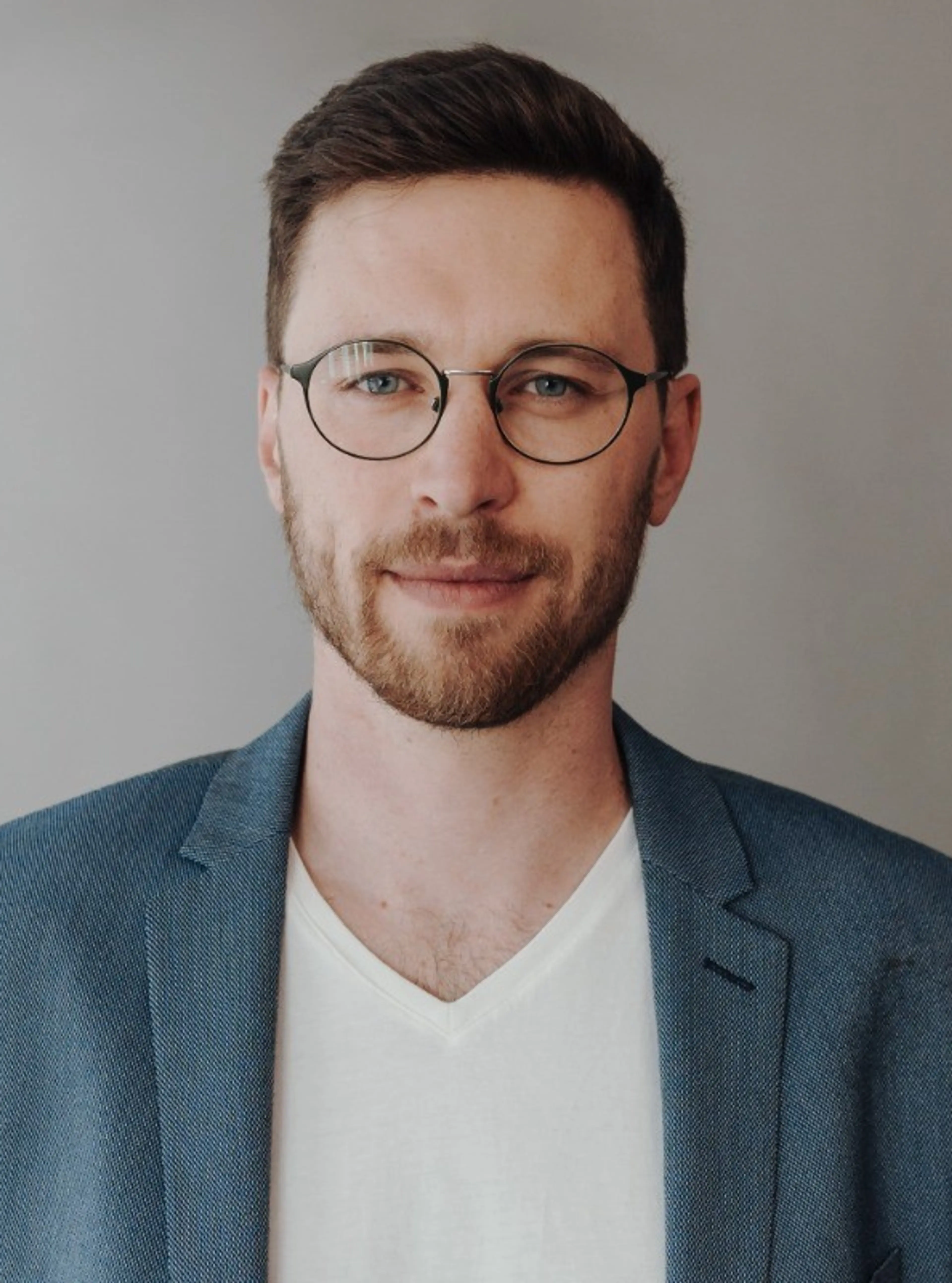 Image of male consultant wearing a blue suit and black glasses