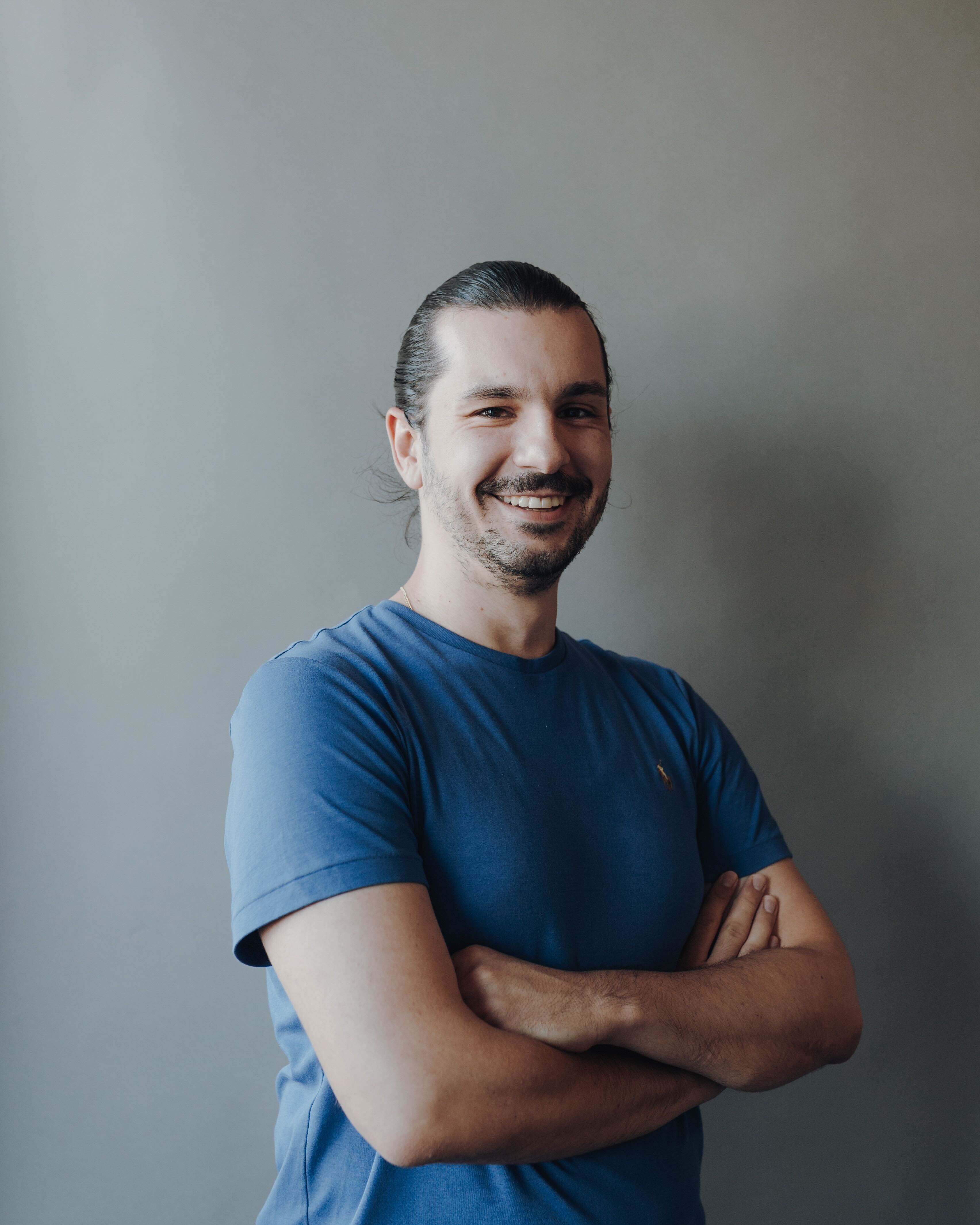 Smiling man wearing a light blue t-shirt.