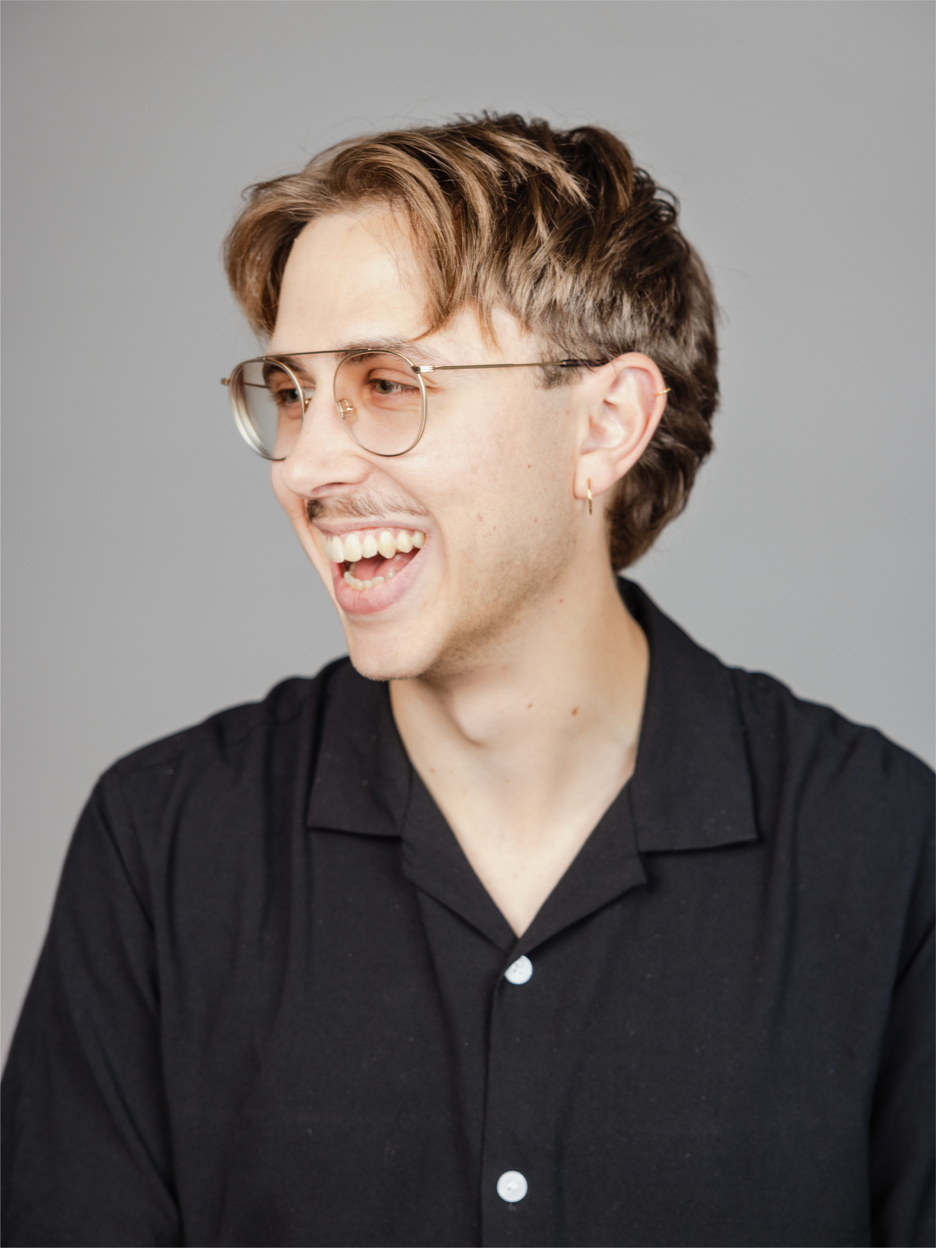 A man with glasses laughing and looking to the left