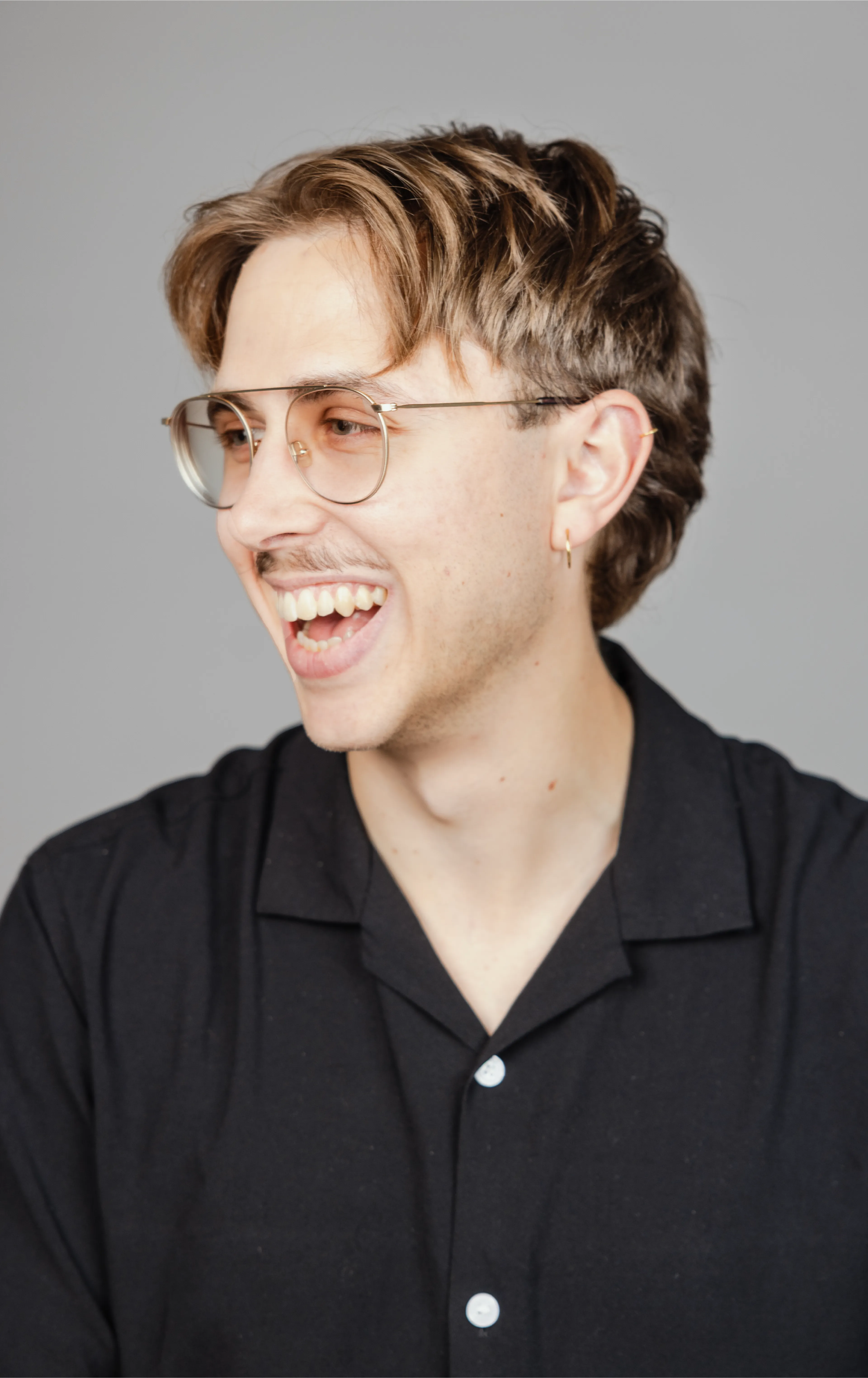 A man with glasses laughing and looking to the left