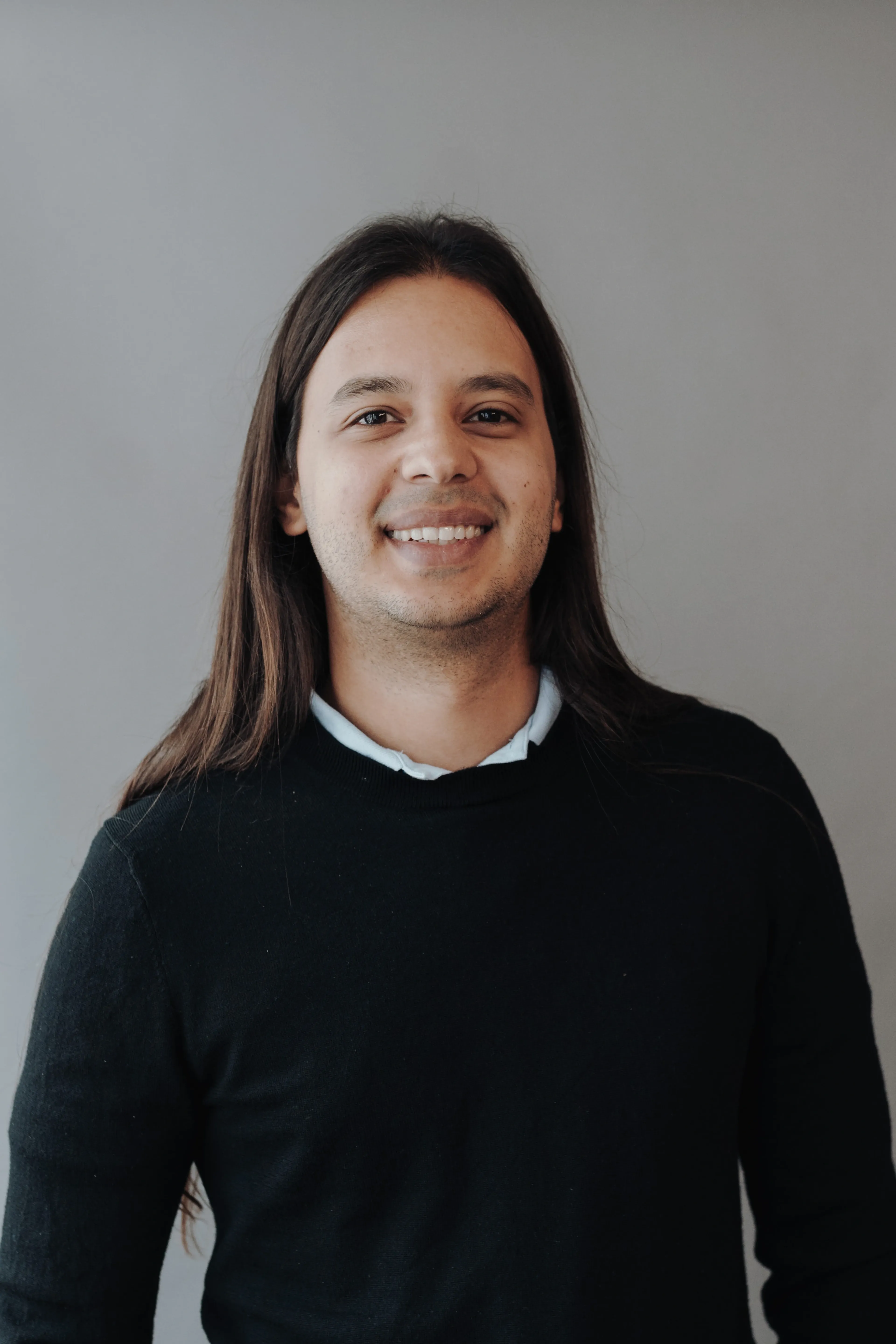 Smiling man with long hair wearing a blue shirt.