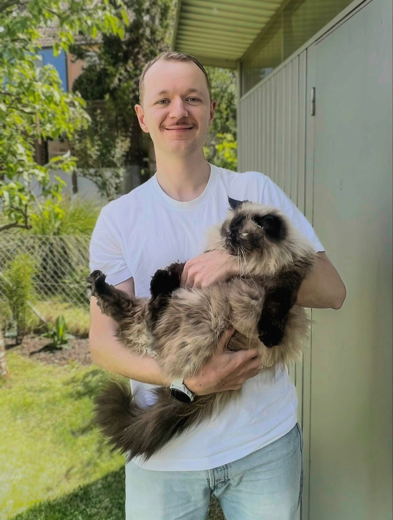 White men with white tshirt and blue jeans holding a dog