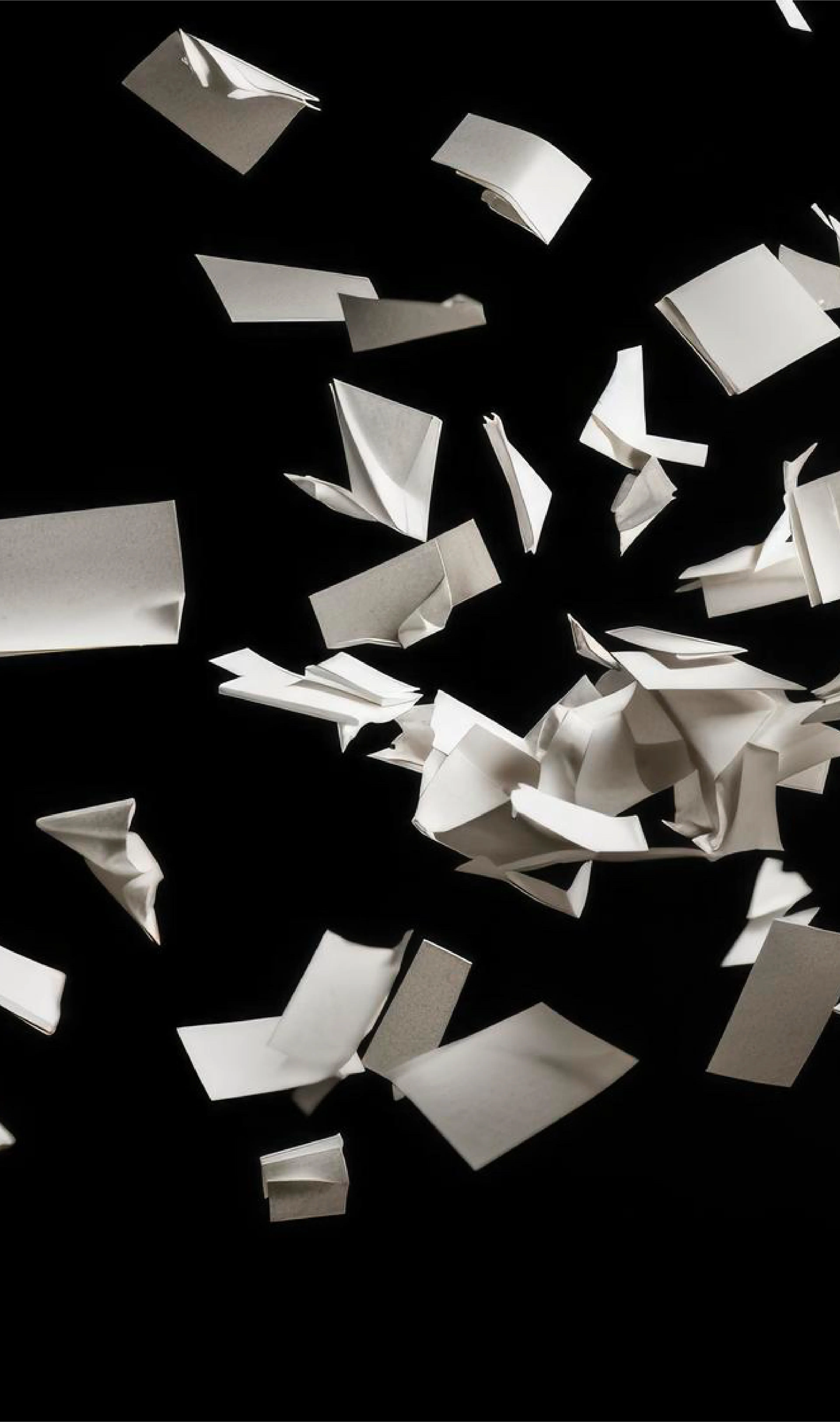 Papers flying in air against a black background.