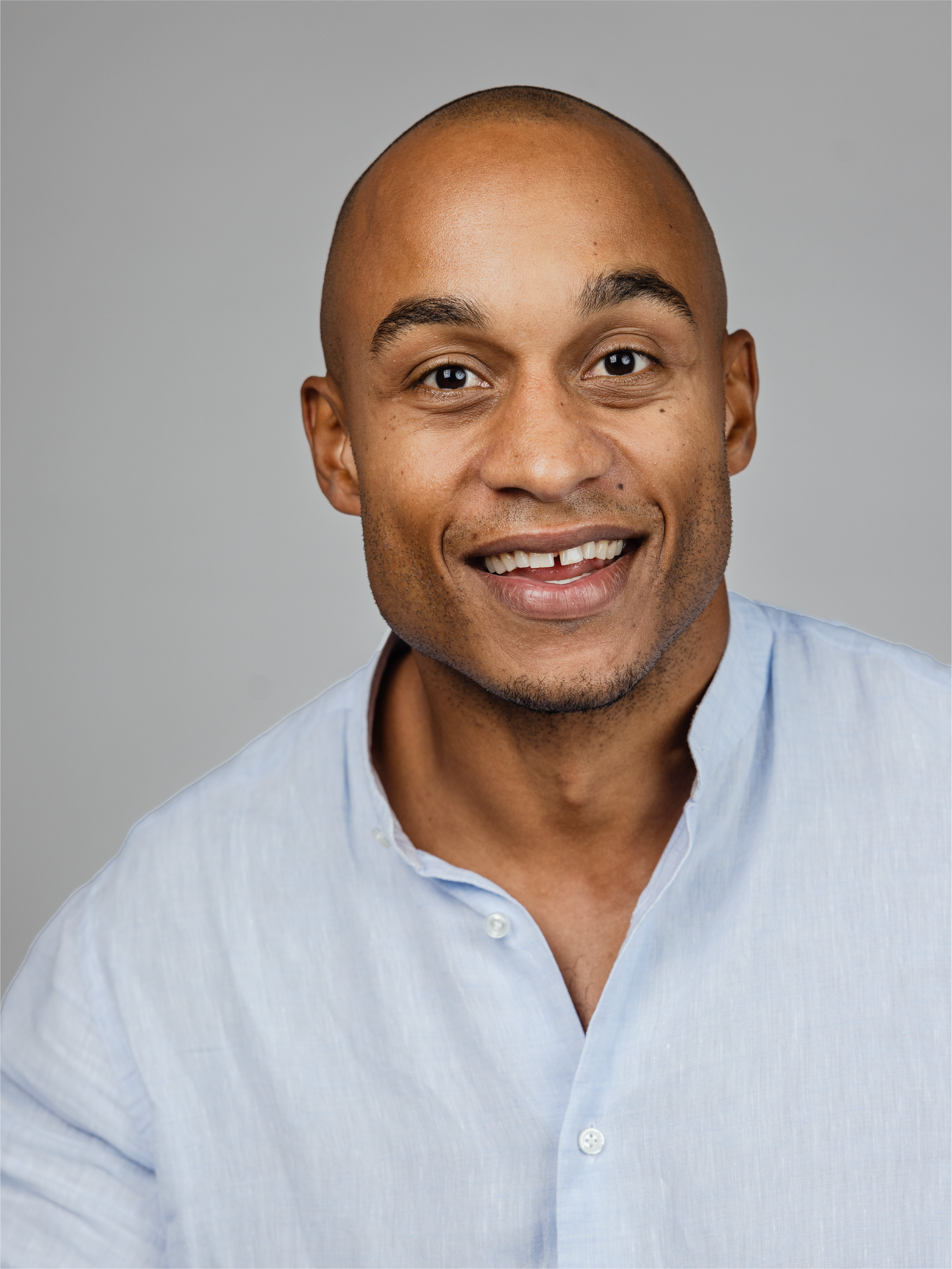 A man looking straight into the camera, smiling slightly with open mouth