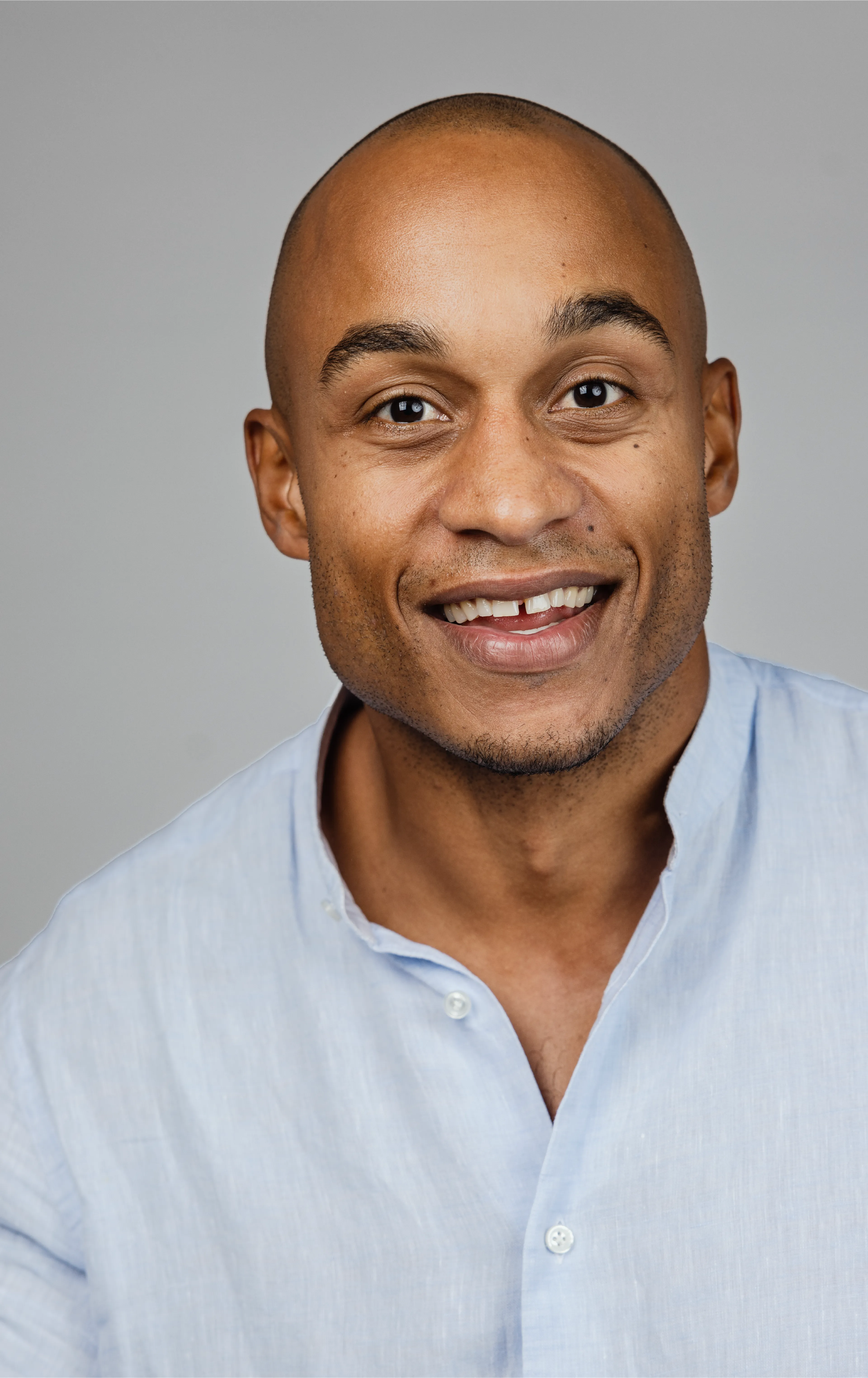 A man looking straight into the camera, smiling slightly with open mouth