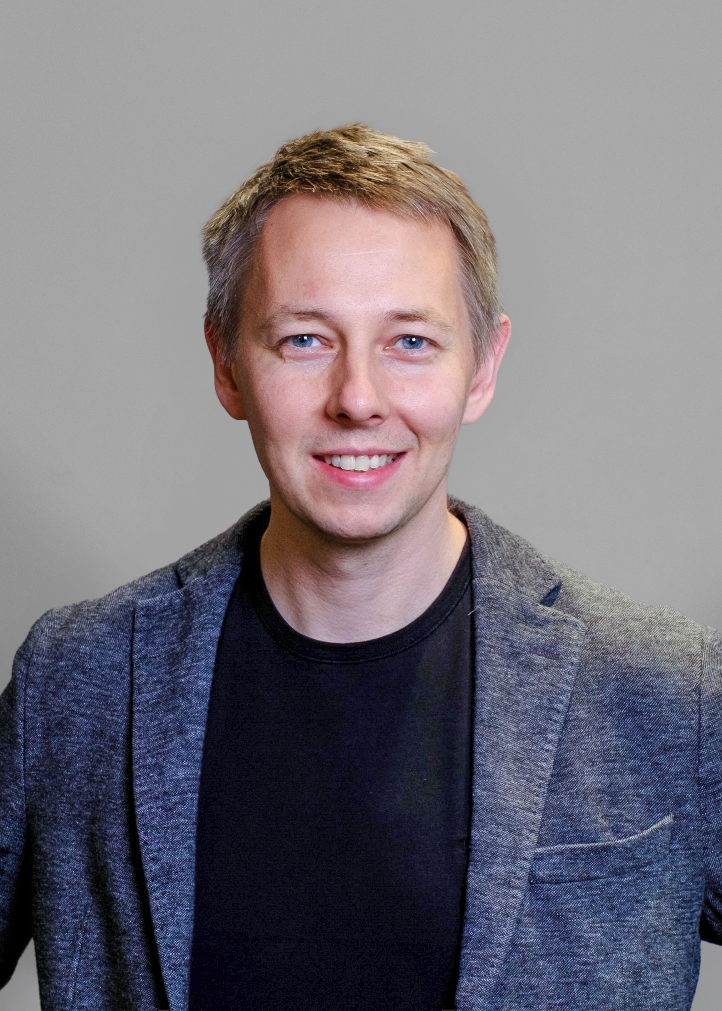Black and white image of male consultant, wearing a black T-shirt and suit