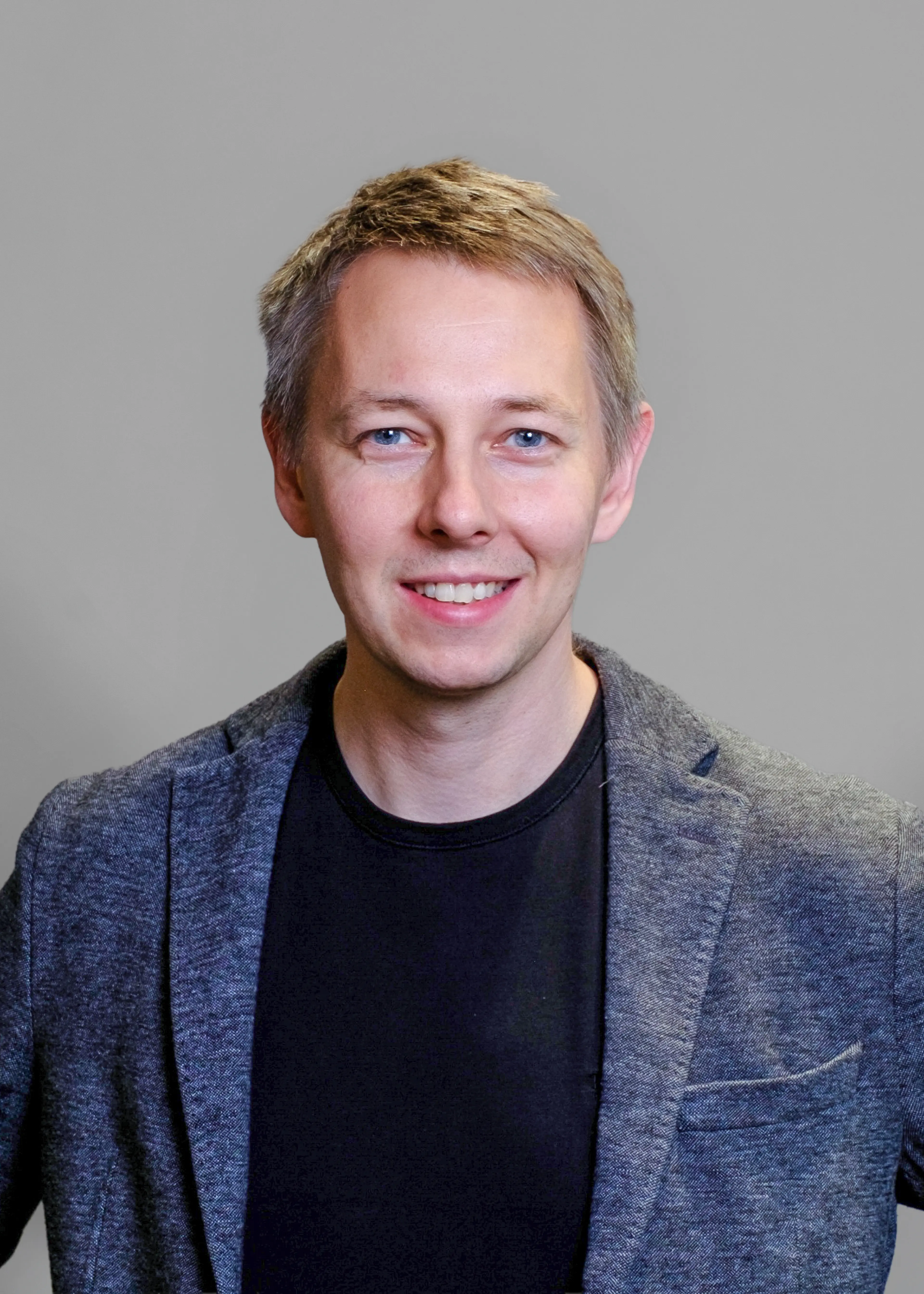 Black and white image of male consultant, wearing a black T-shirt and suit