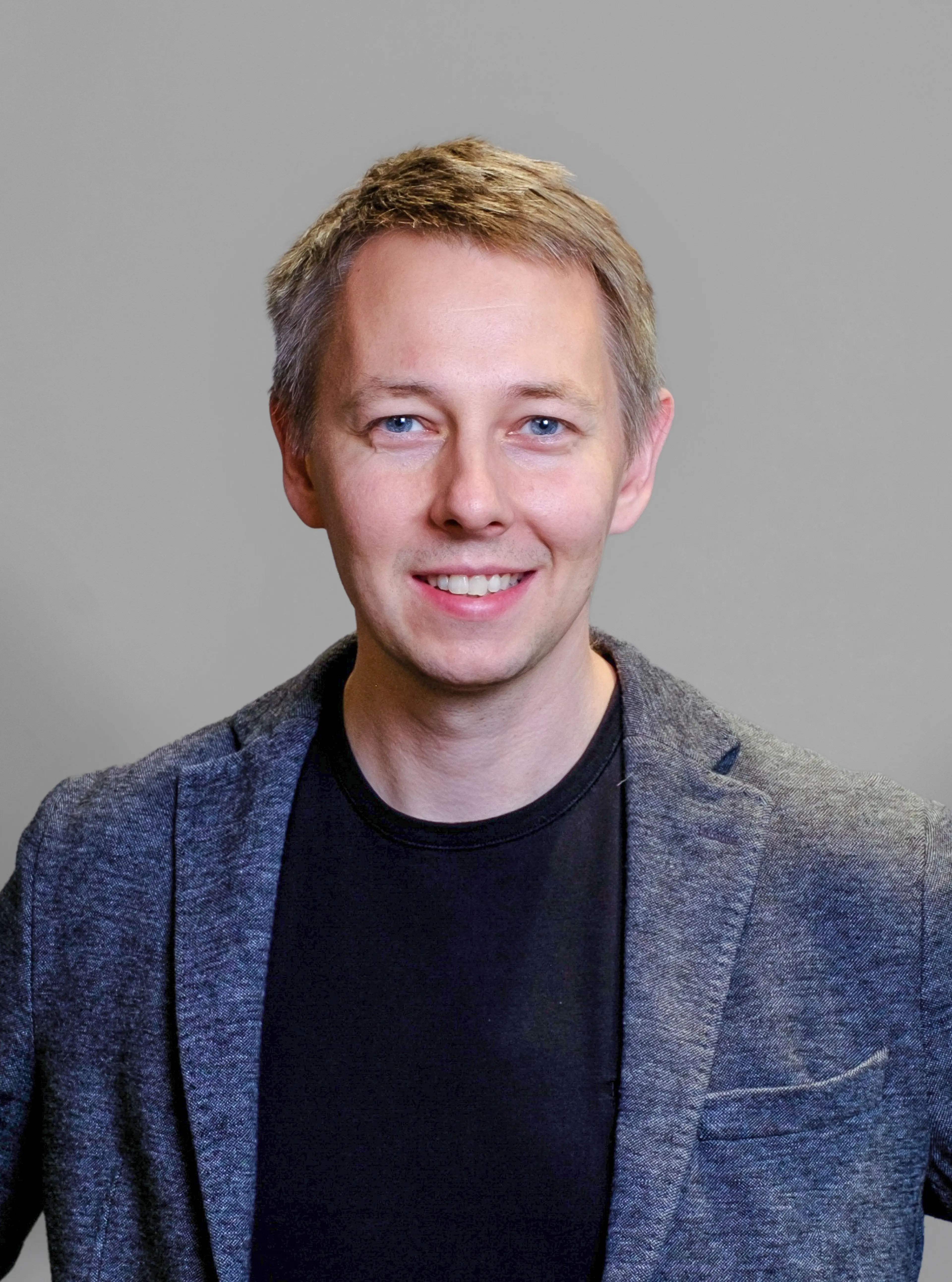 Black and white image of male consultant, wearing a black T-shirt and suit