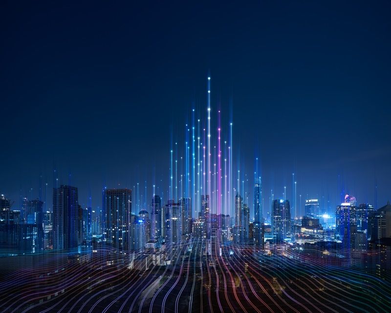 Futuristic cityscape at night with illuminated skyscrapers and digital data lines depicting connectivity and technological innovation."