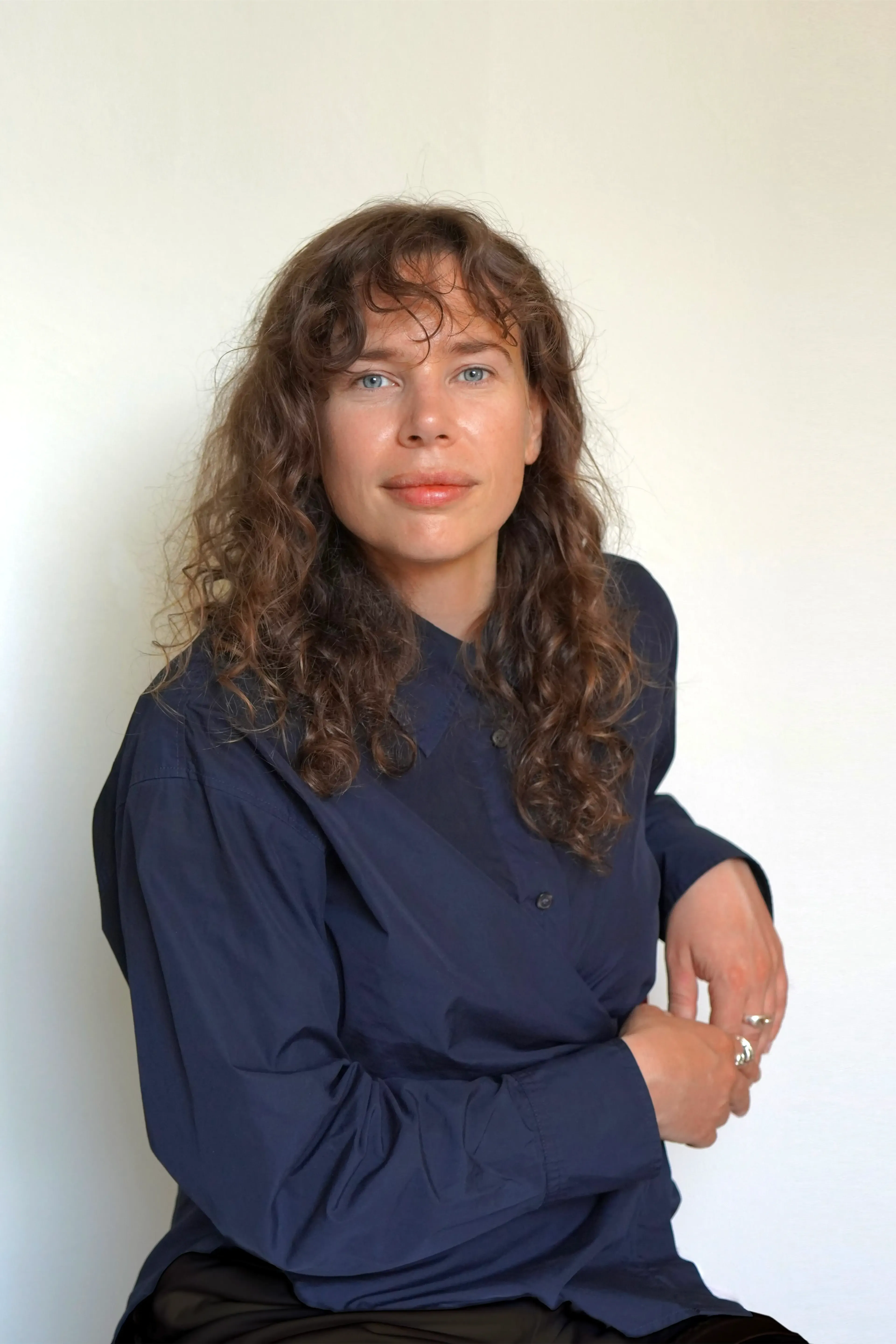 Woman with curly hair wearing a blue shirt.