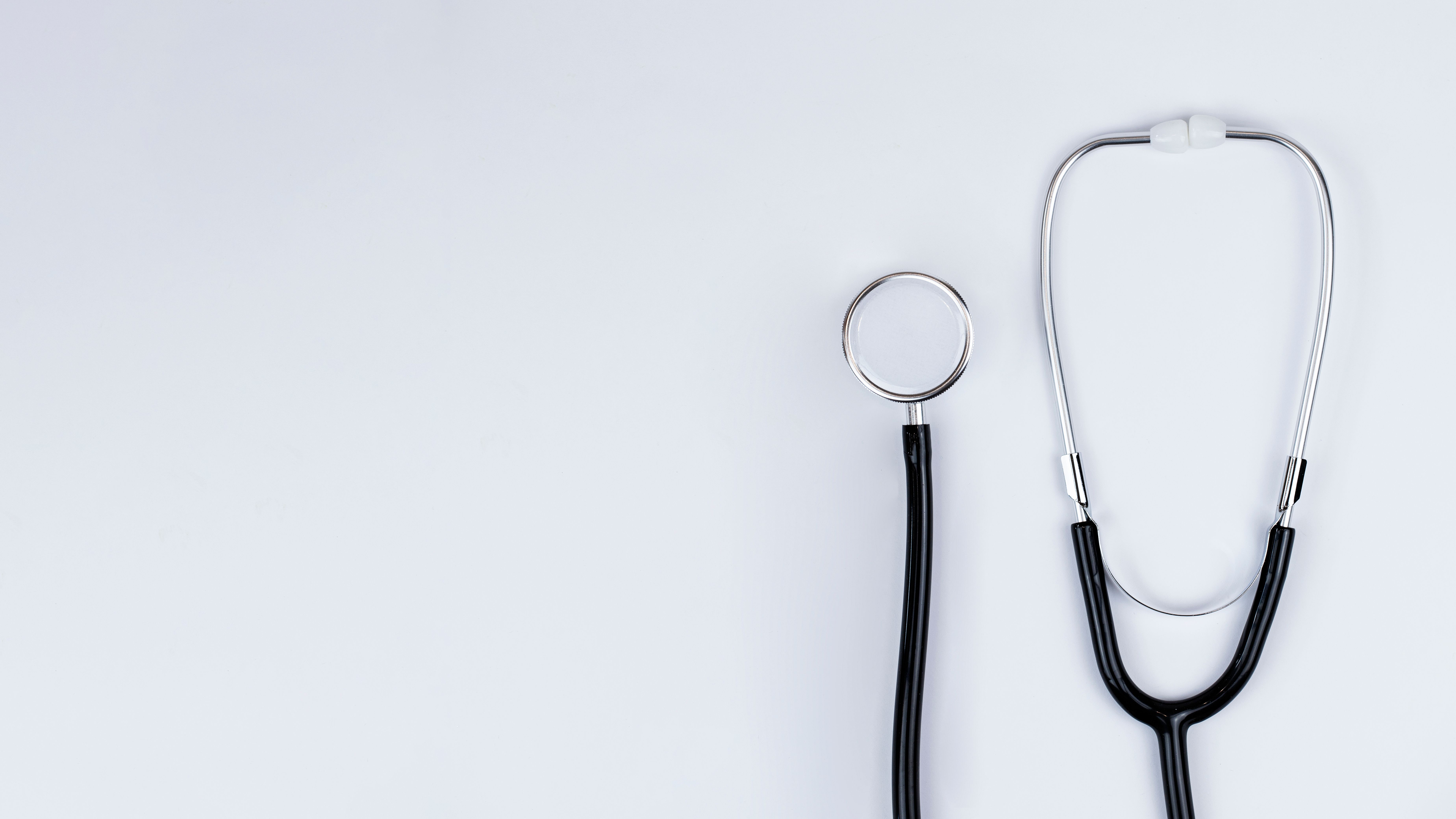  Blue stethoscope and blue pens resting on the pocket of a white medical lab coat, symbolizing healthcare and the medical profession
